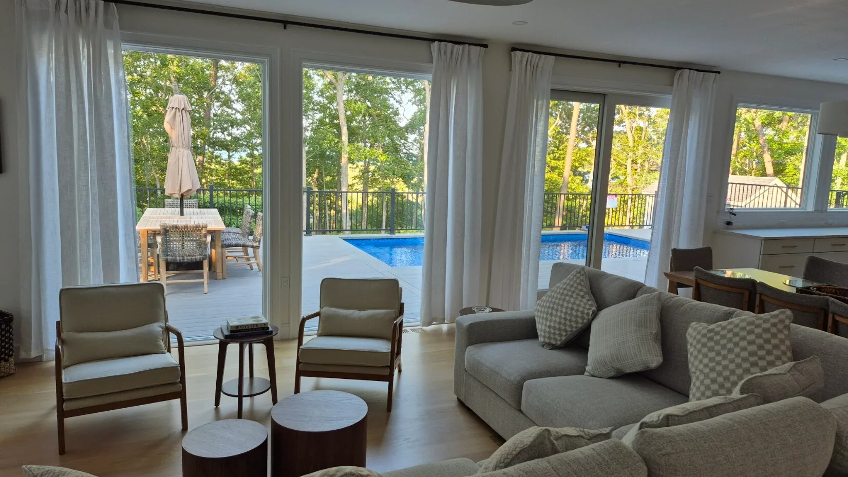 Una sala luminosa con asientos junto a grandes ventanas que dan a una piscina.