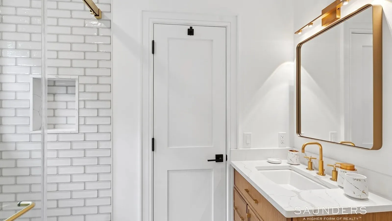 Un baño luminoso con lavabo, espejo y pared de ducha con azulejos.