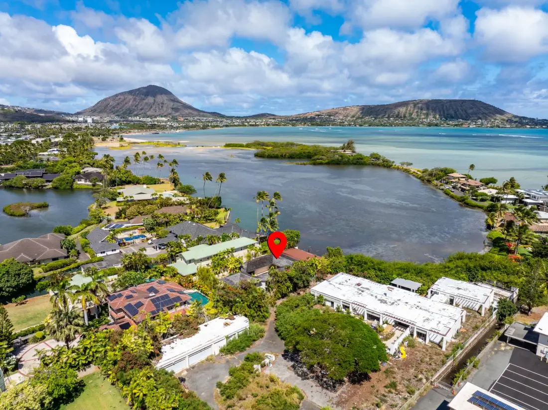 Aerial view of a coastal neighborhood surrounding a lagoon, with mountains in the distance.
