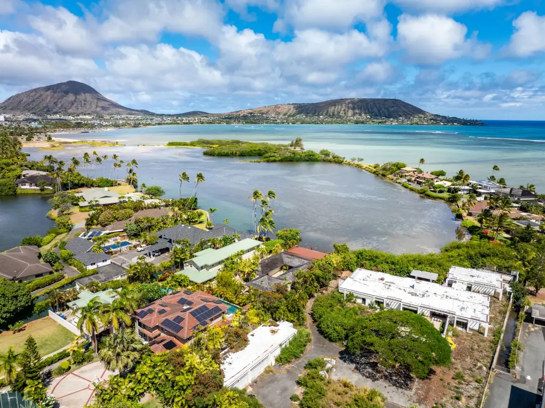 Aerial view of a coastal lagoon bordered by homes and green hills.