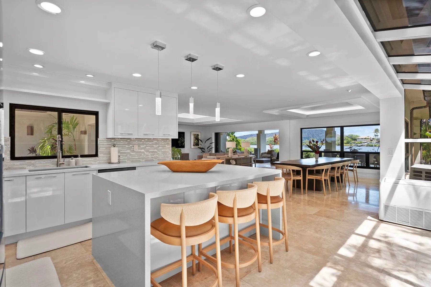 A bright open-plan kitchen and dining area with a large island and wide windows.