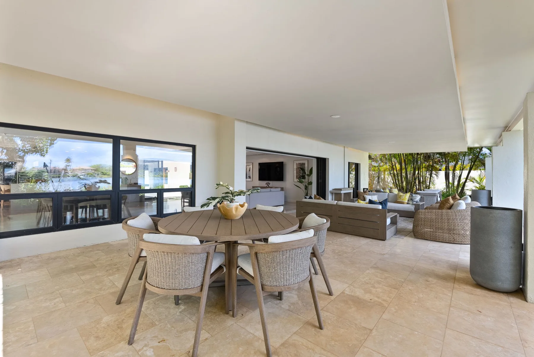 A covered patio dining area with a round table and lounge seating.