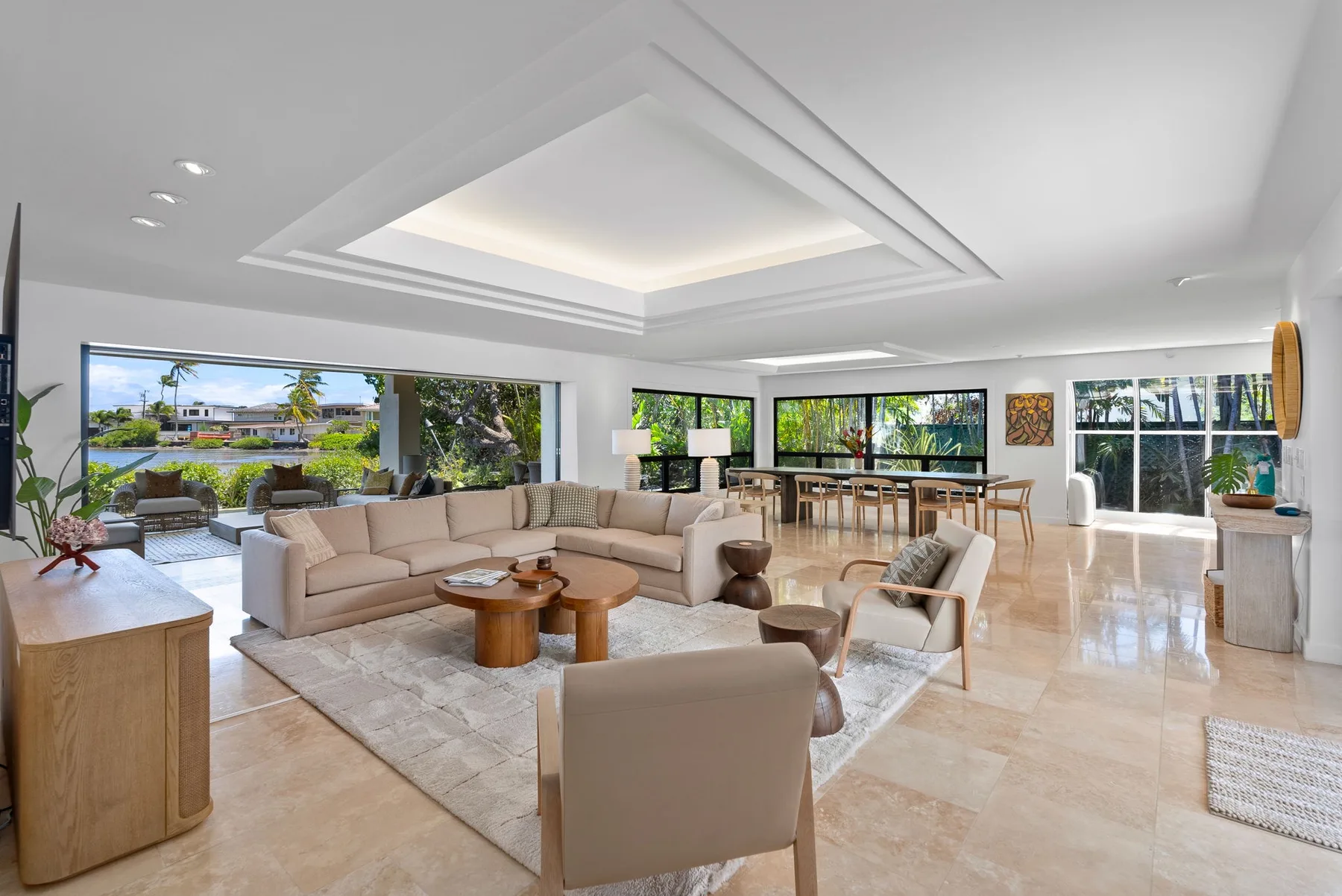 A bright open-plan living and dining area with large windows and neutral seating.