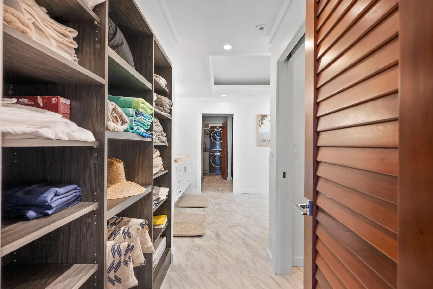 A walk-in closet with open shelving filled with folded linens and clothing.