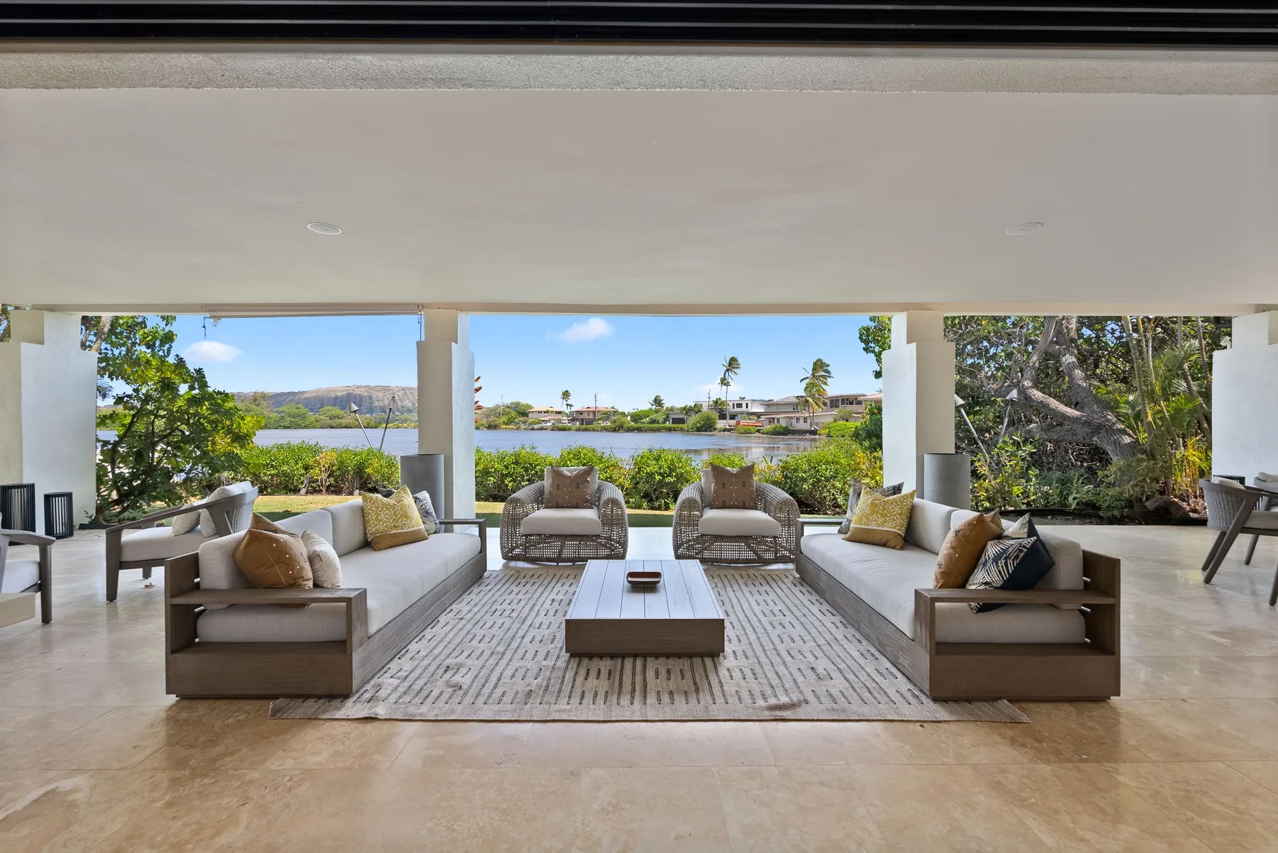An open-air lounge with seating arranged around a low table and views of greenery.