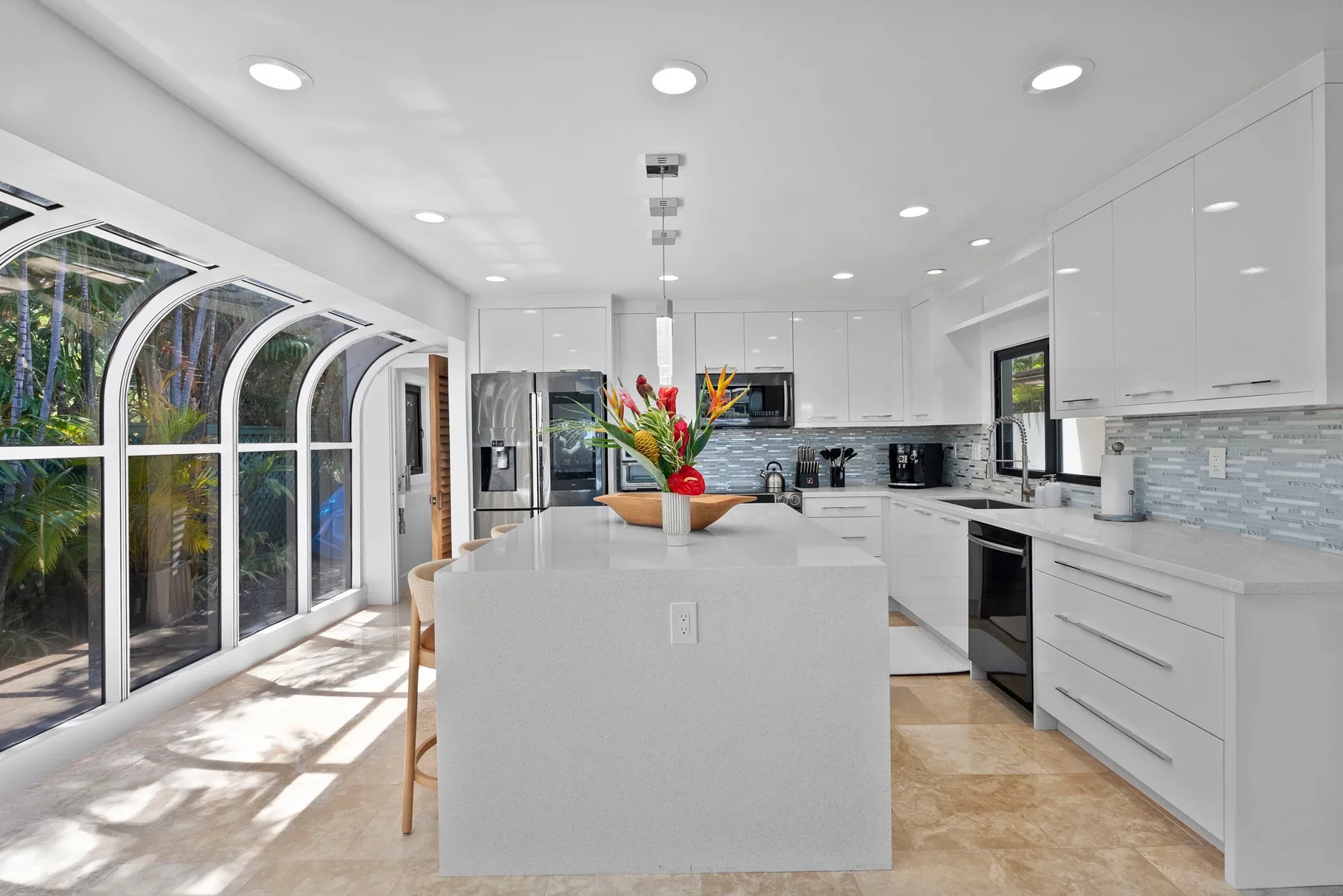 A bright modern kitchen with a central island and large arched windows.
