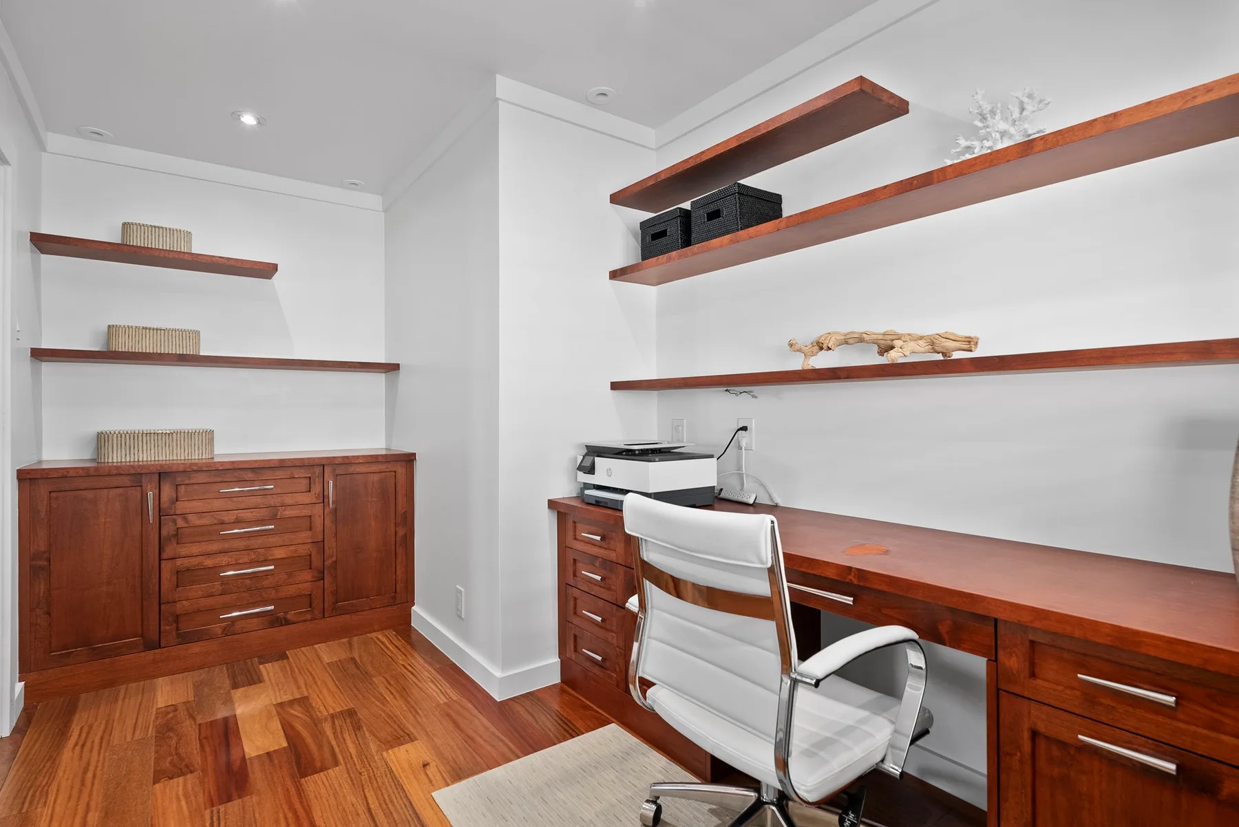 A home office with a wooden desk, shelving, and an office chair.