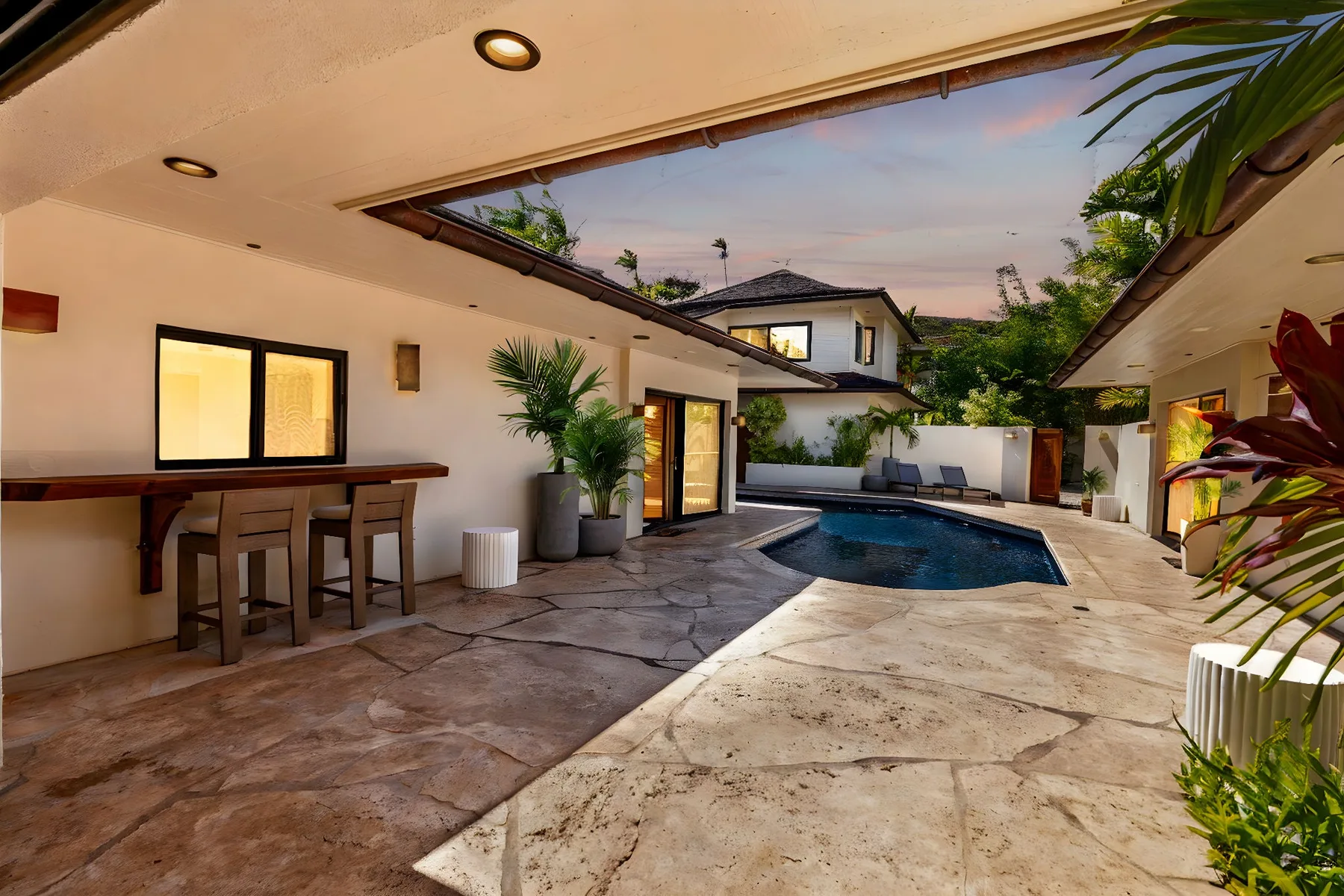 A covered outdoor patio opens onto a swimming pool, with a counter and seating along the wall.