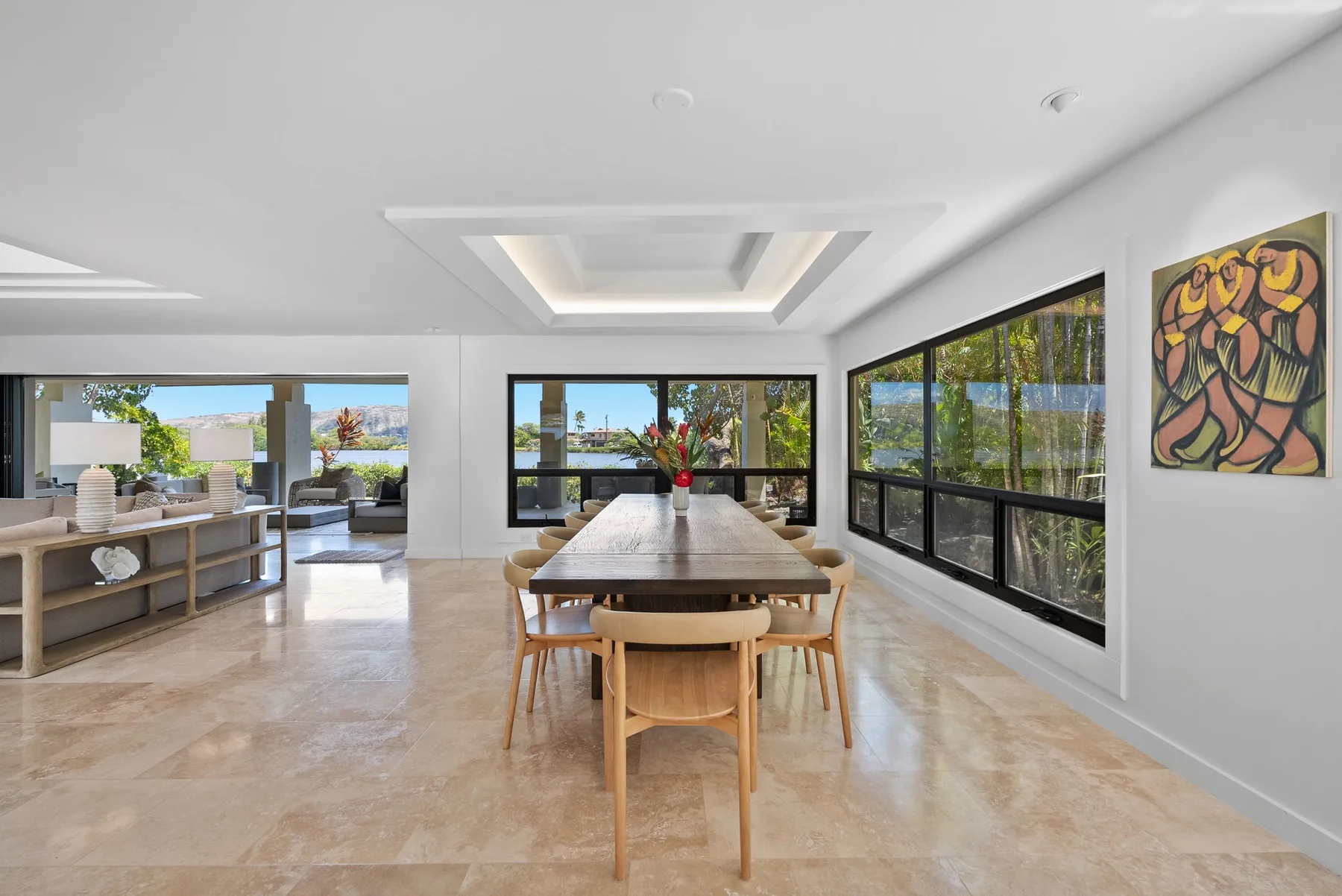 A bright dining area with a long table, seating, and large windows.