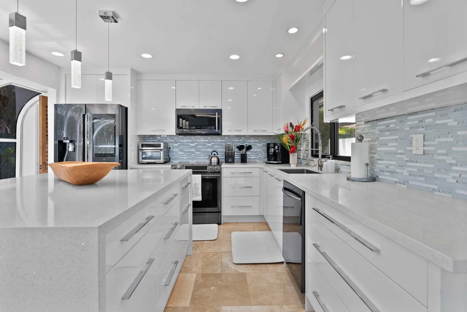 A bright modern kitchen with white cabinetry and broad countertops.