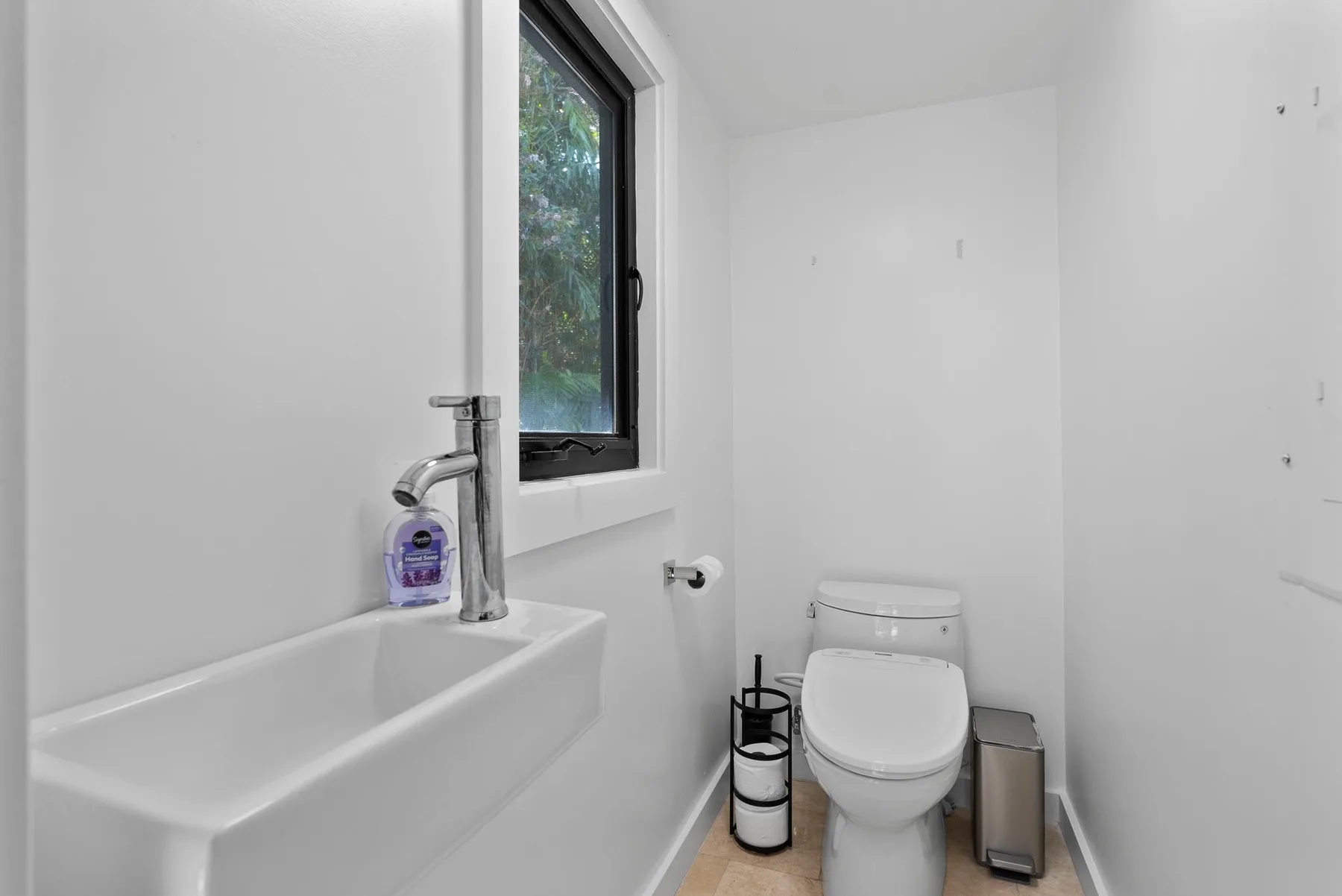 A bright bathroom with a sink, toilet, and window.