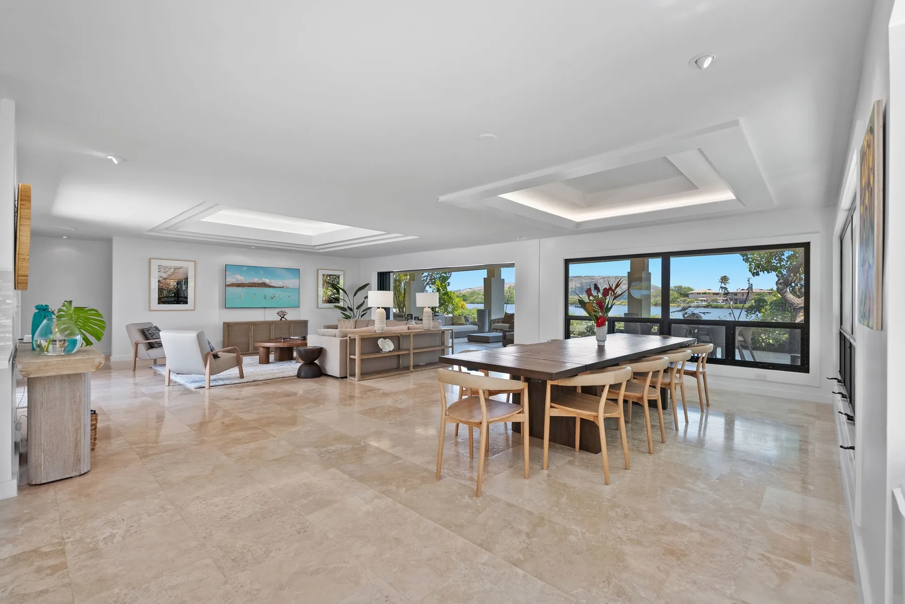 A bright open-plan living and dining room with seating beside large windows.