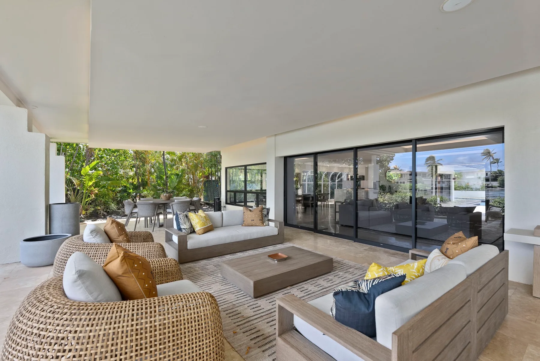 A covered outdoor patio opens onto a seating area with a low table and glass doors.