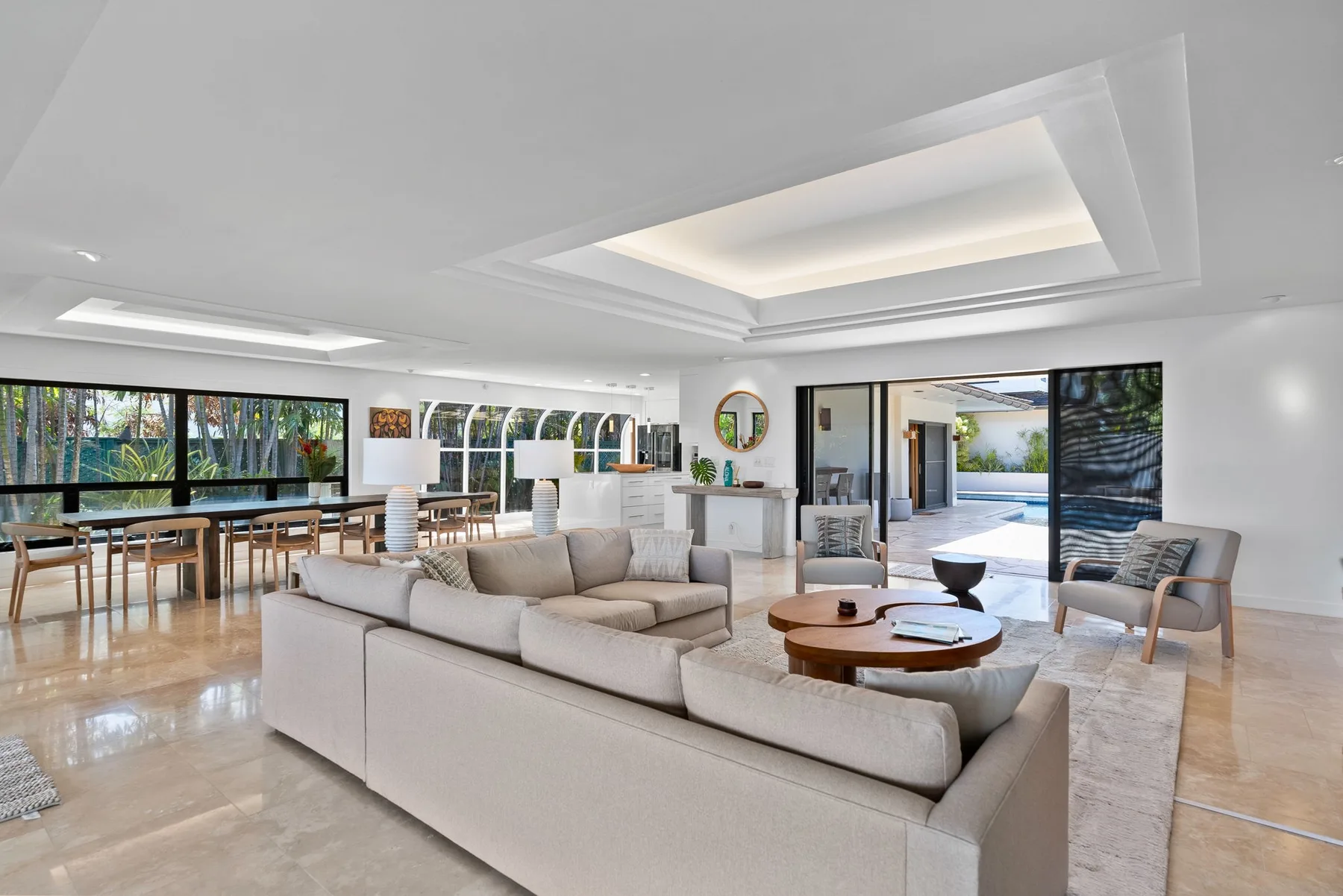 A bright living room with seating, a dining area, and wide windows.