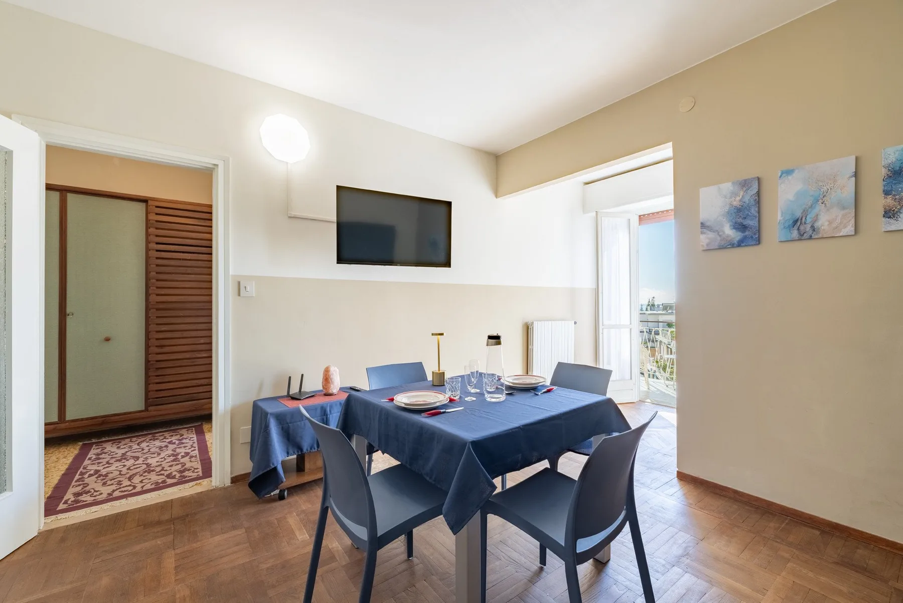 A dining area with a table set beneath a wall-mounted television.