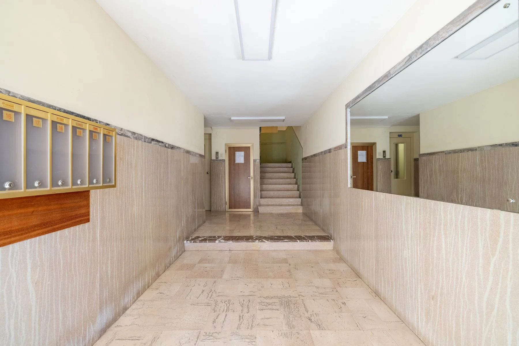 An indoor hallway with mailboxes along the wall and stairs at the far end.