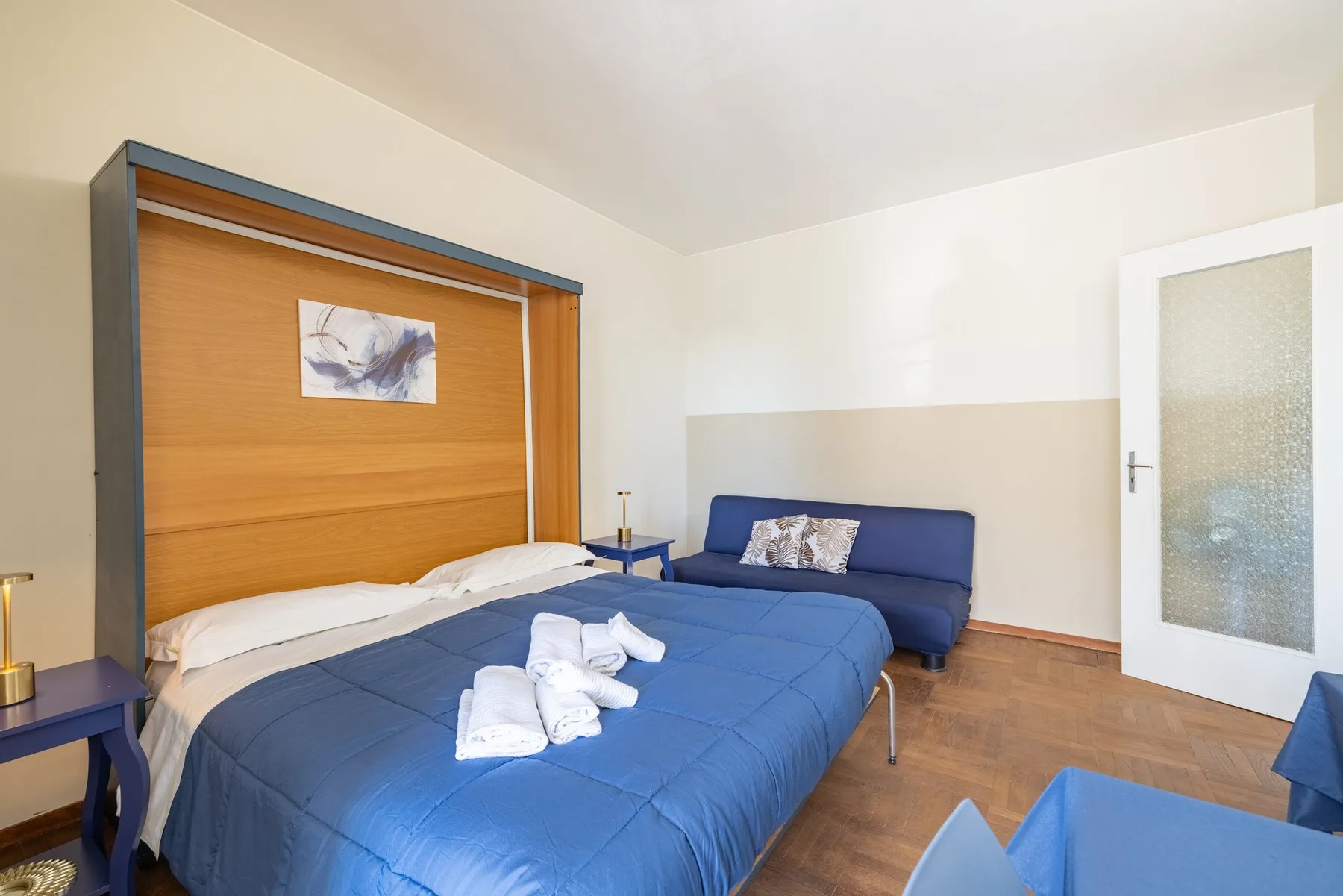 A bedroom with a blue-covered bed and matching seating.