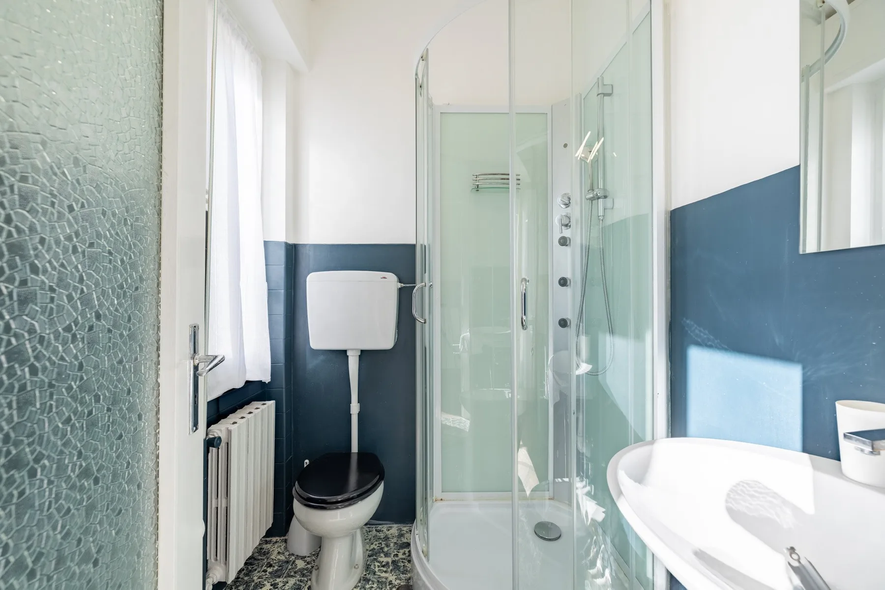 A bathroom with a glass shower, toilet, and sink.