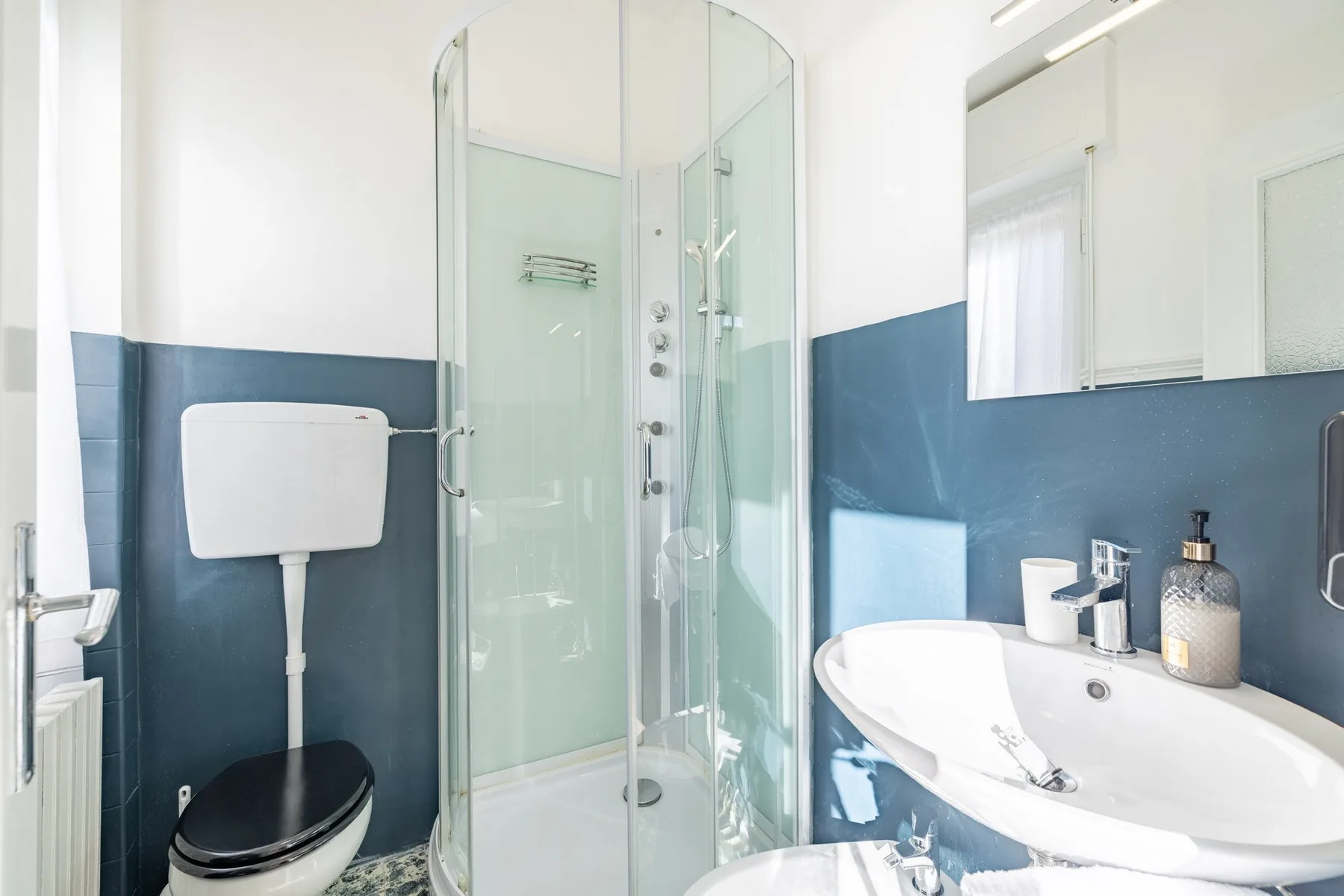 A bathroom with a glass shower, toilet, and sink.