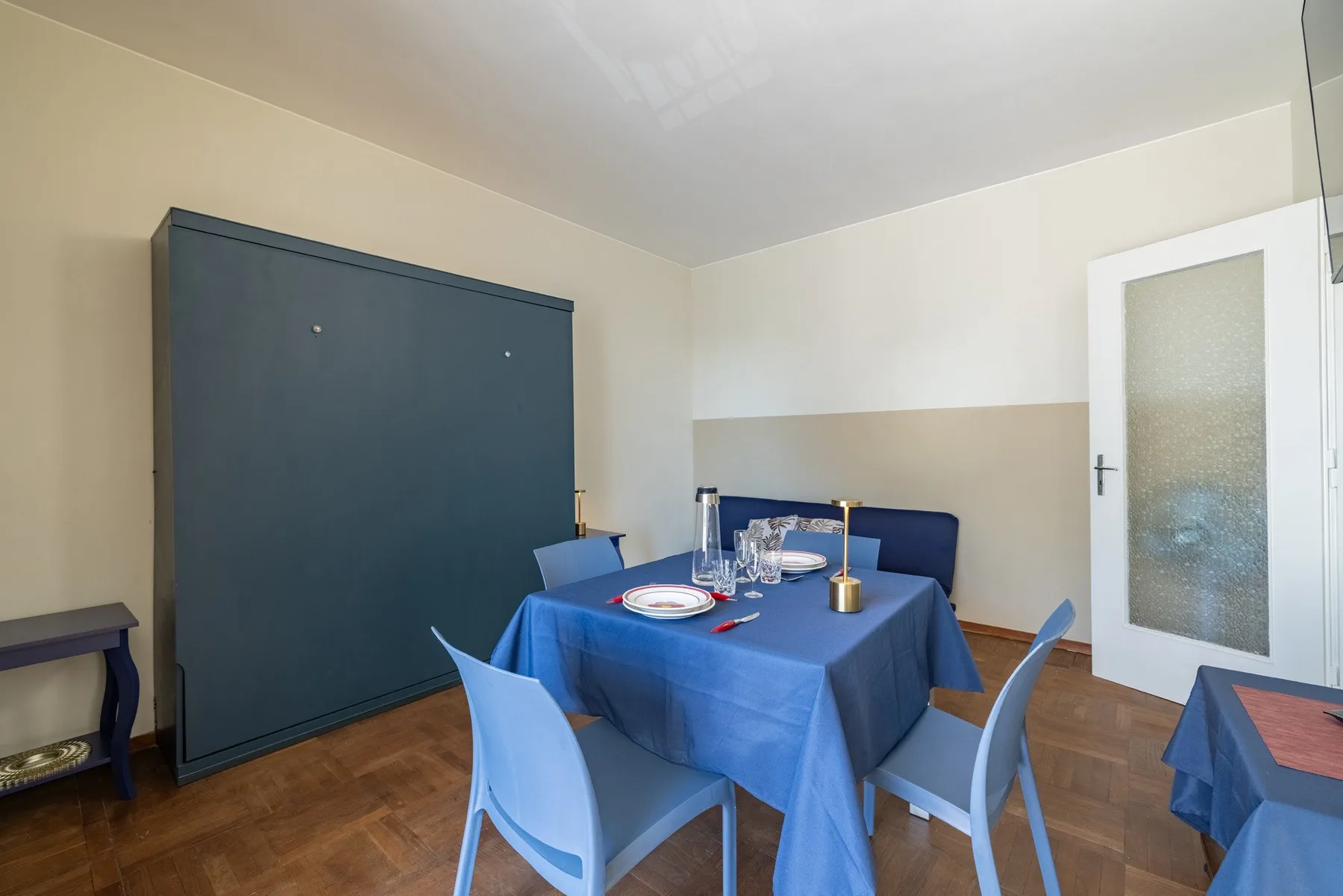 A dining area with a blue-covered table set with plates and glasses.