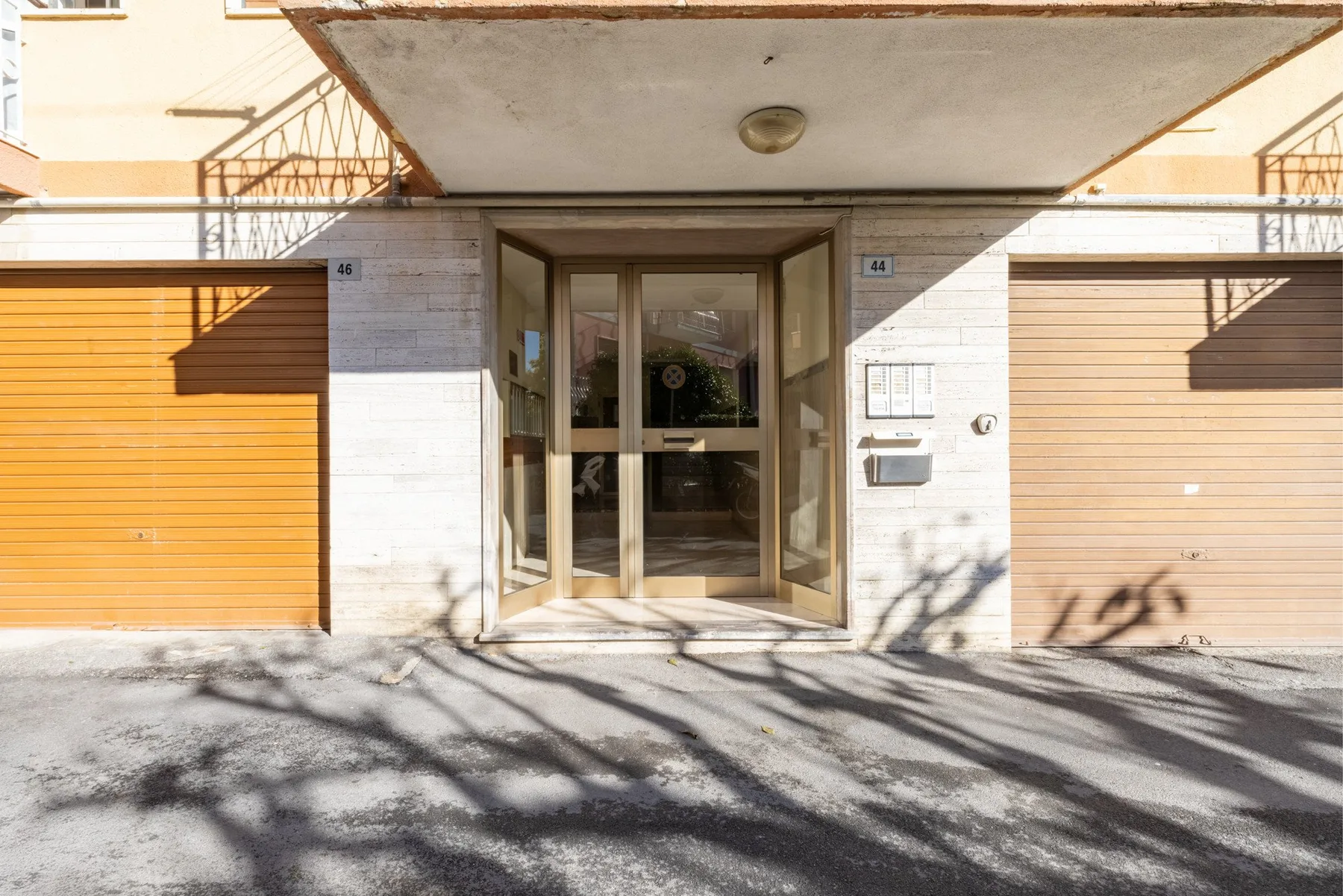 Building entrance with glass doors between two orange garage doors.