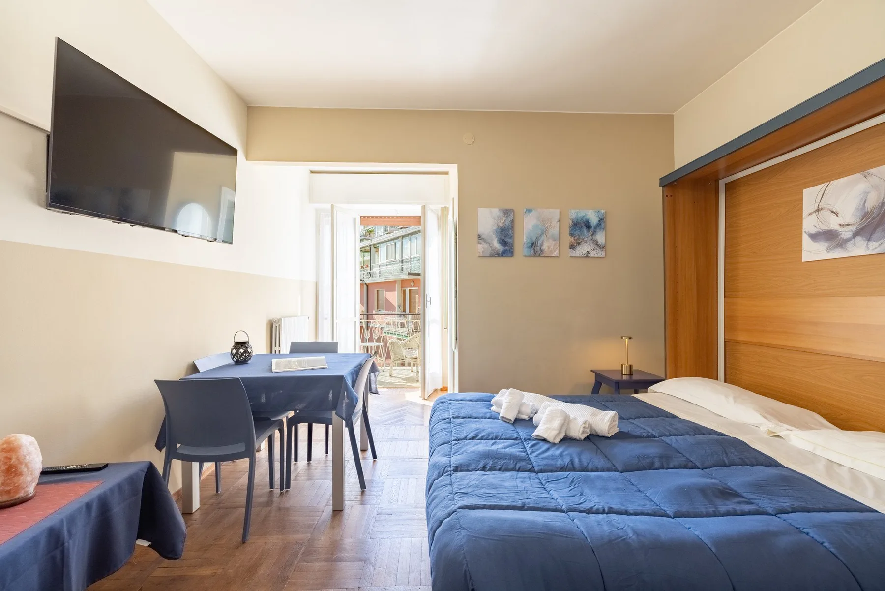 A bedroom with a blue bed beside a small dining area.