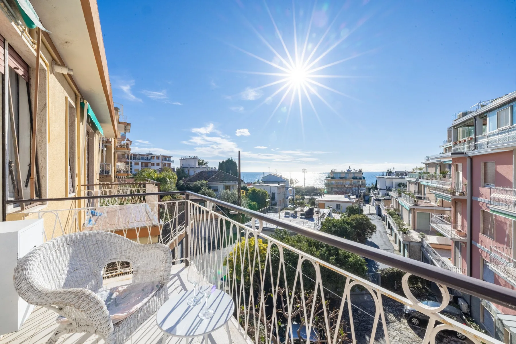 A sunny balcony overlooks a street lined with buildings.