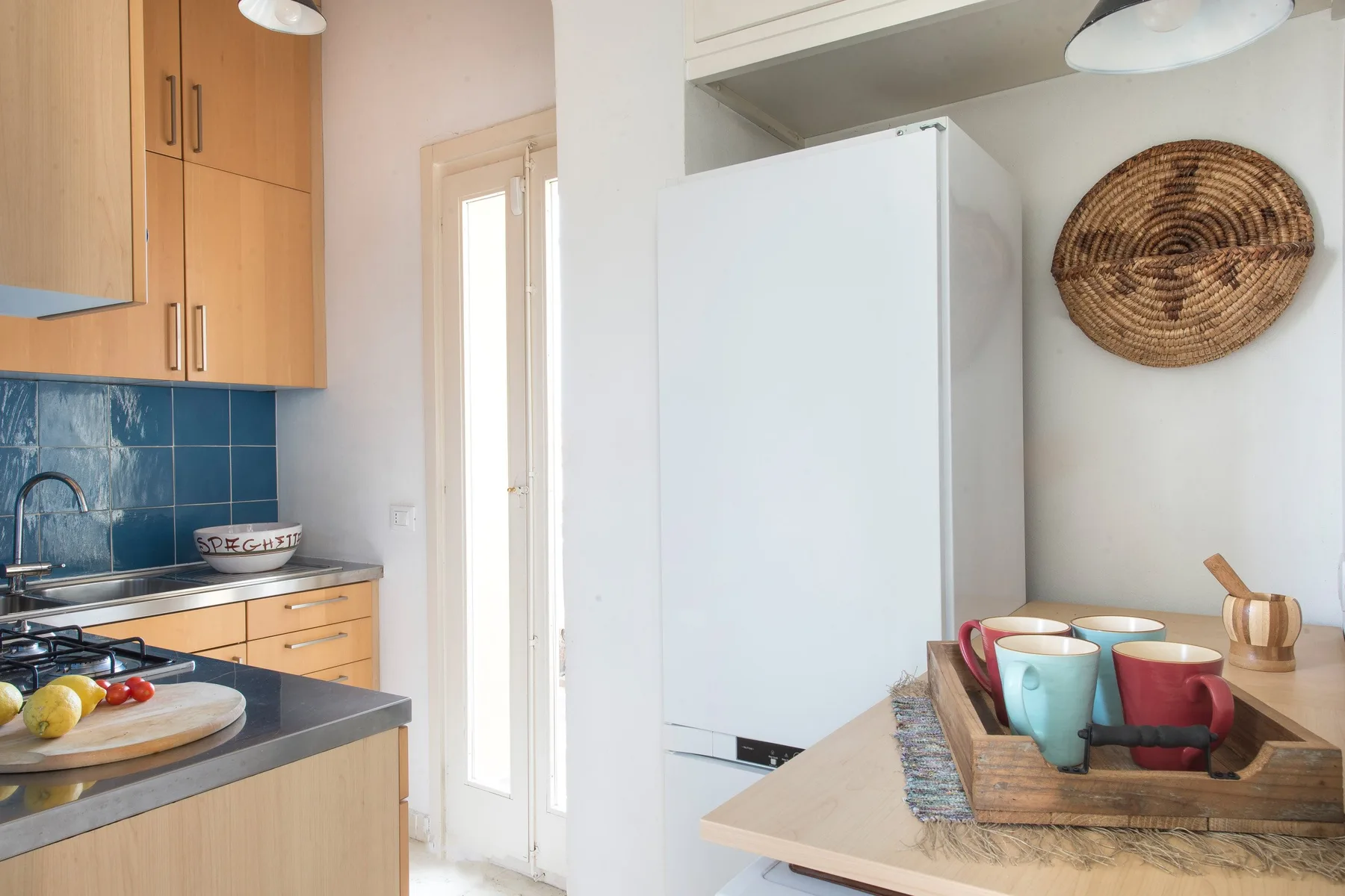 A bright kitchen with wooden cabinets, blue tile, and a dining table.
