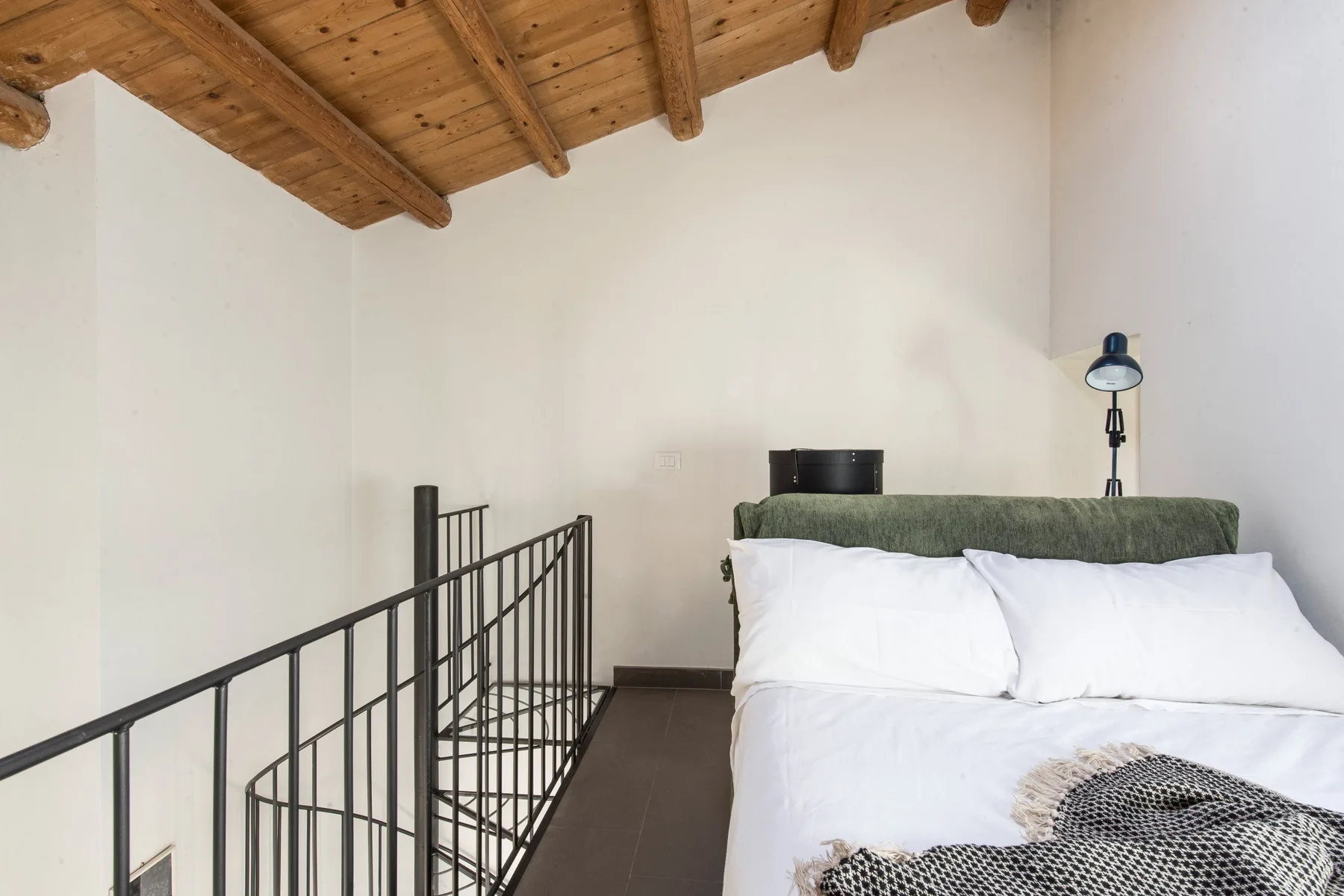 A bedroom with a bed beneath a sloped wooden ceiling.