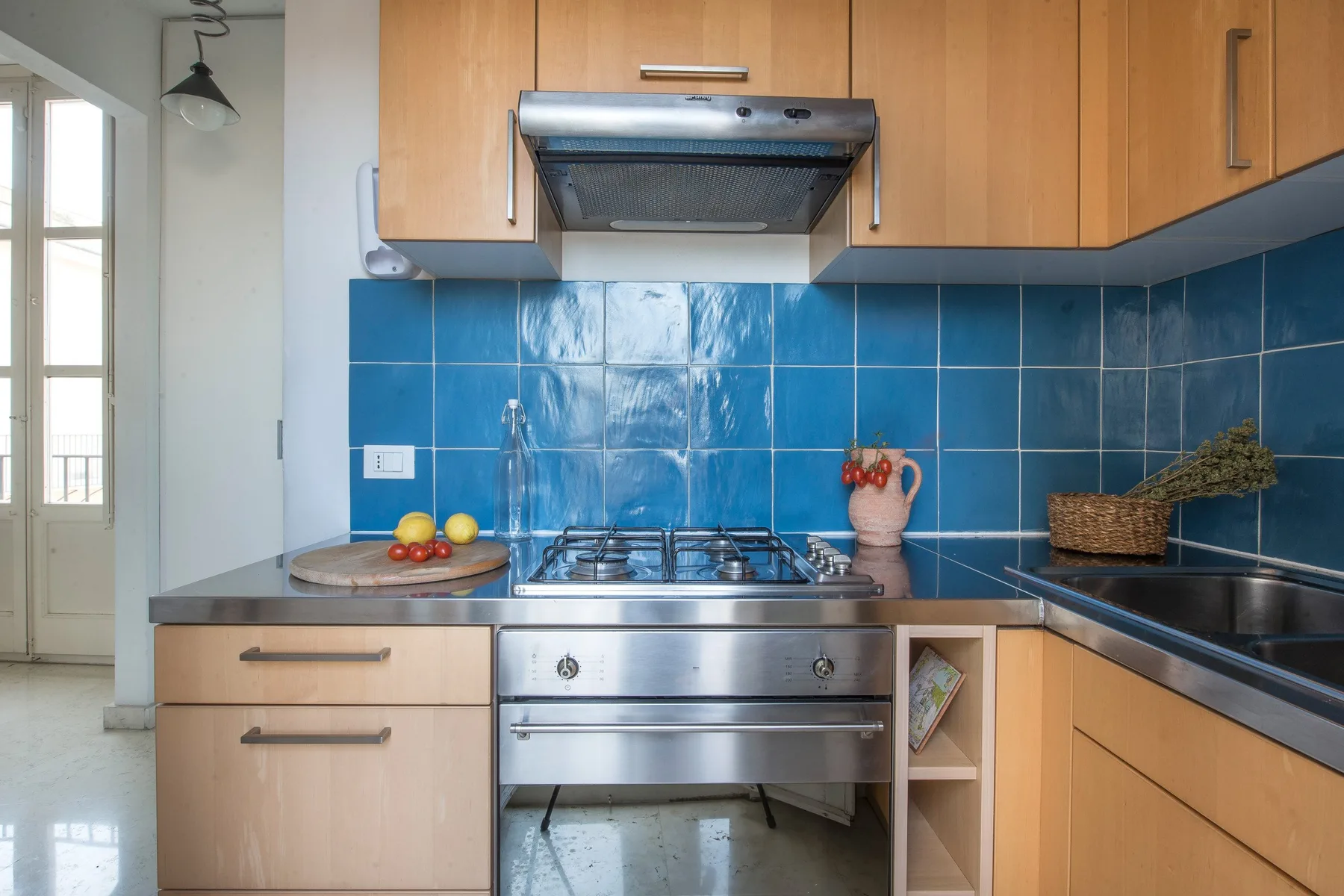 A kitchen with wooden cabinets, a stainless steel range, and blue tile walls.
