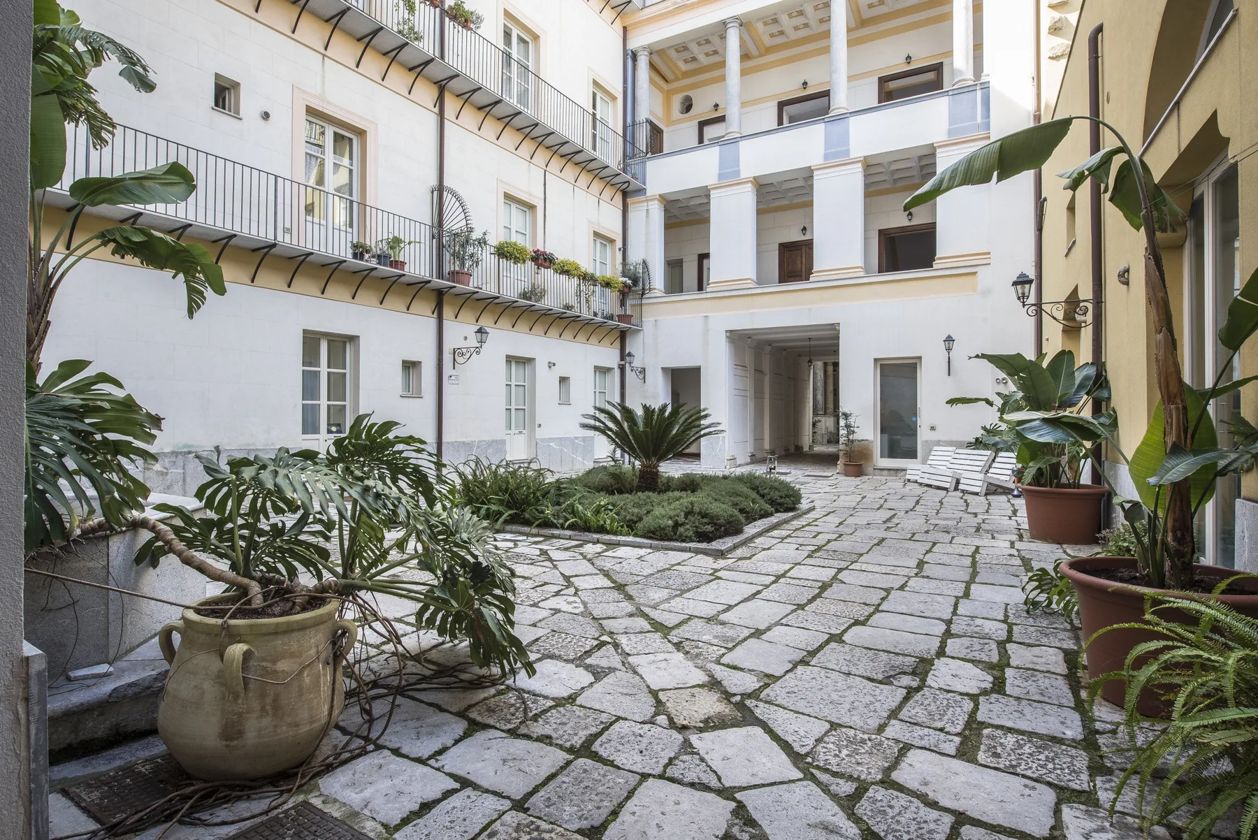 A tiled courtyard with balconies and potted plants.