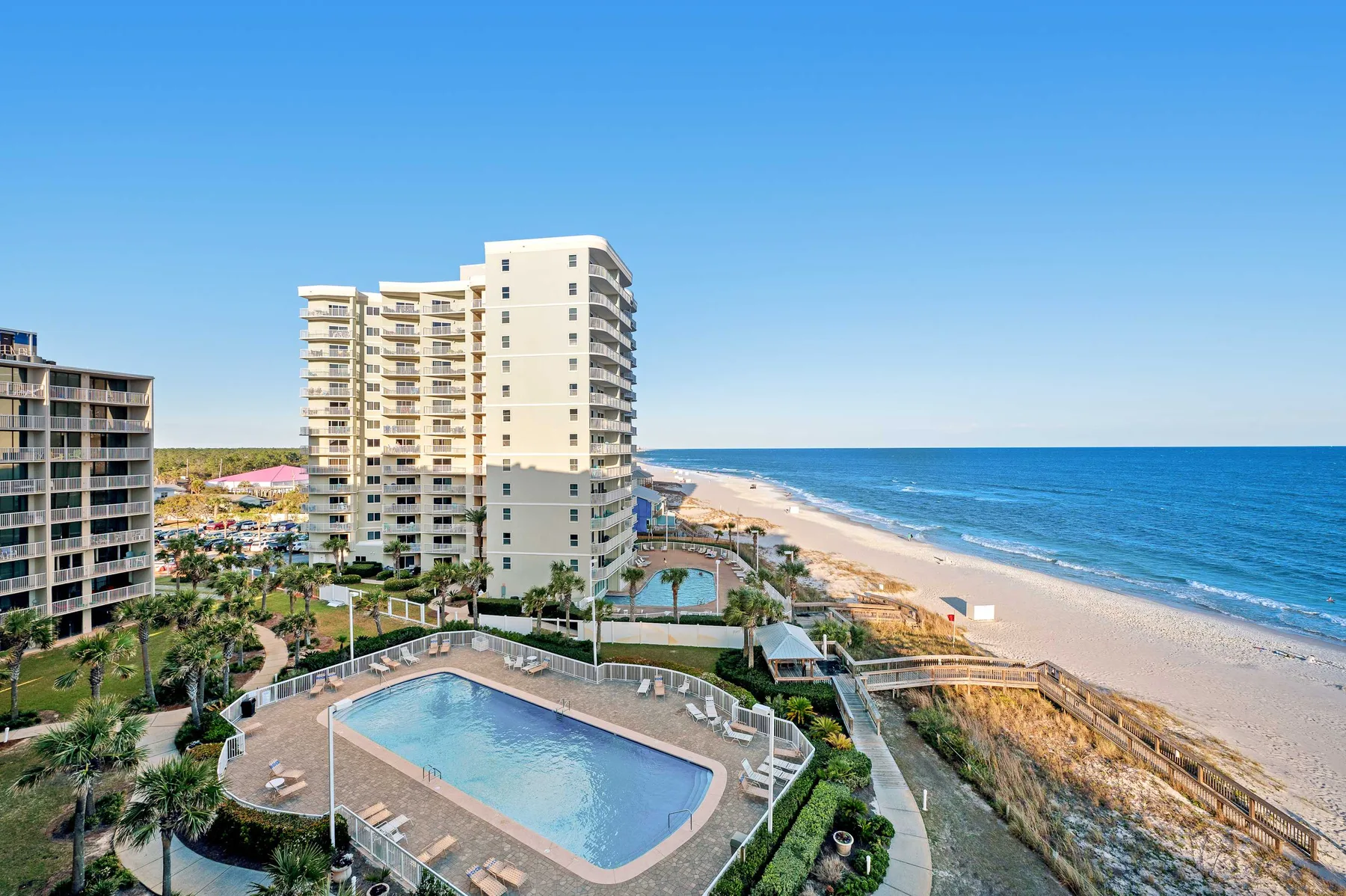 A beachfront residential complex with a swimming pool beside the ocean.