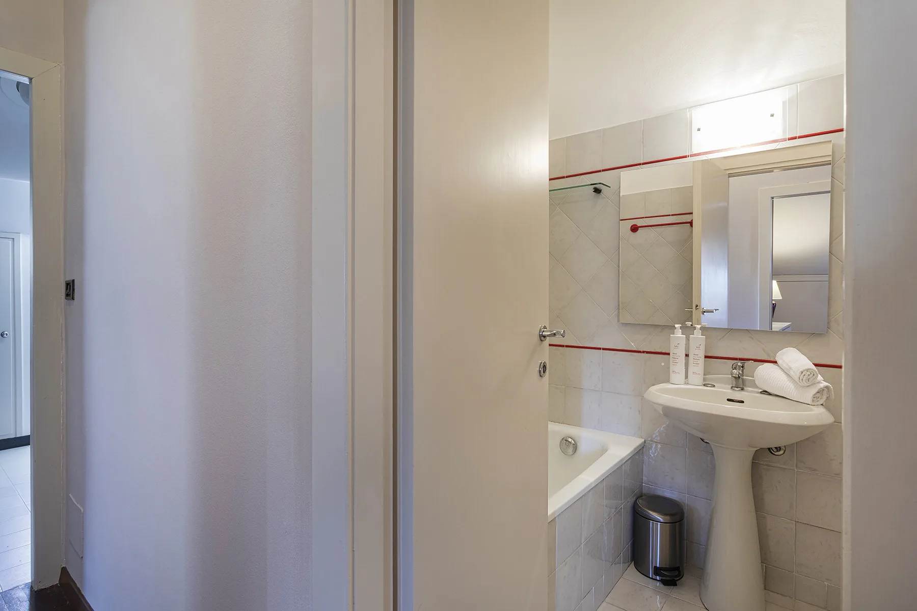 Un baño con lavabo, espejo y parte de una bañera a la vista.