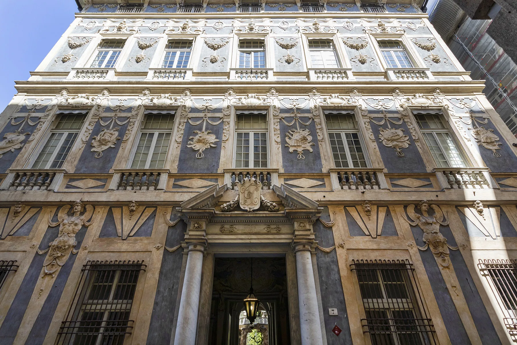 Fachada de un edificio histórico ornamentado, con filas de ventanas y una entrada central.