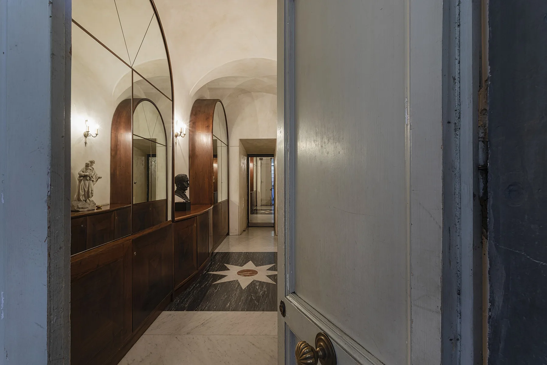 Un pasillo abovedado con muebles de madera oscura y un suelo con una estrella.