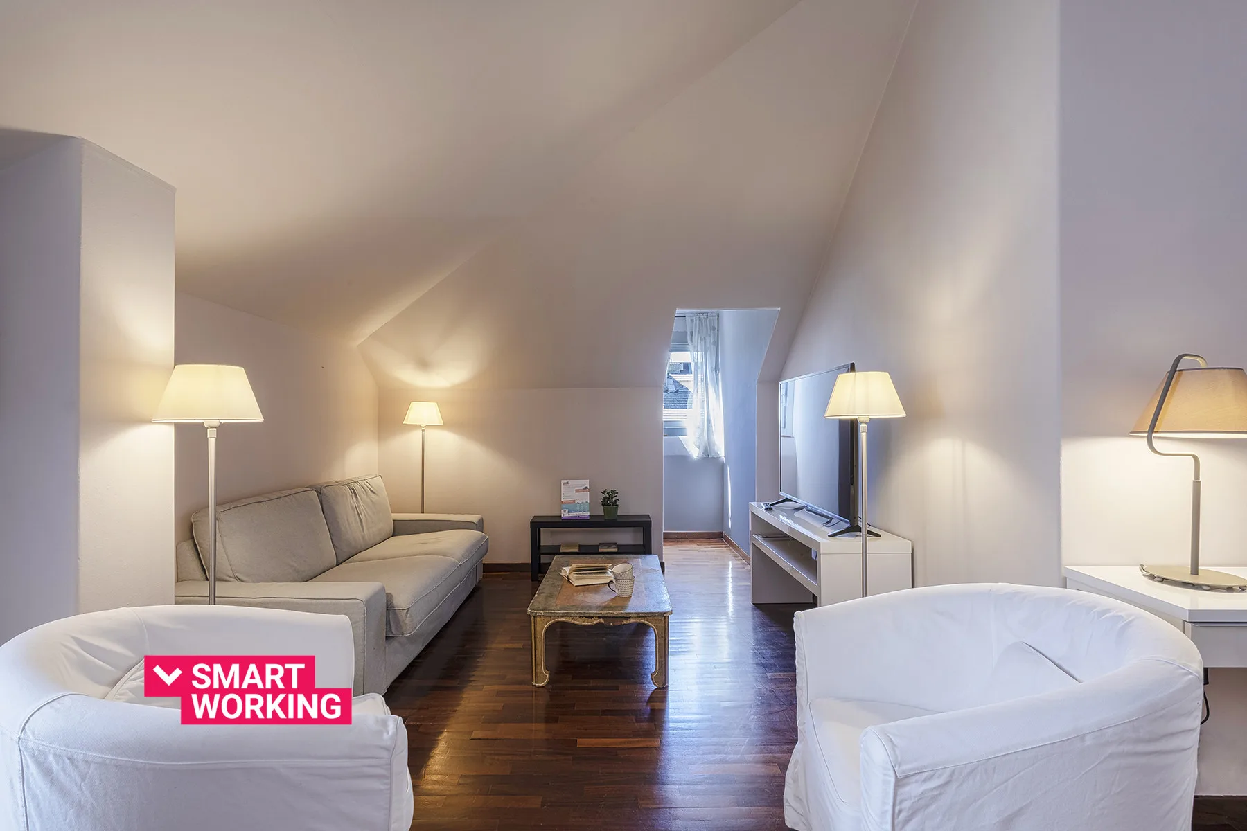 Una sala luminosa con asientos, una mesa de centro y un televisor.