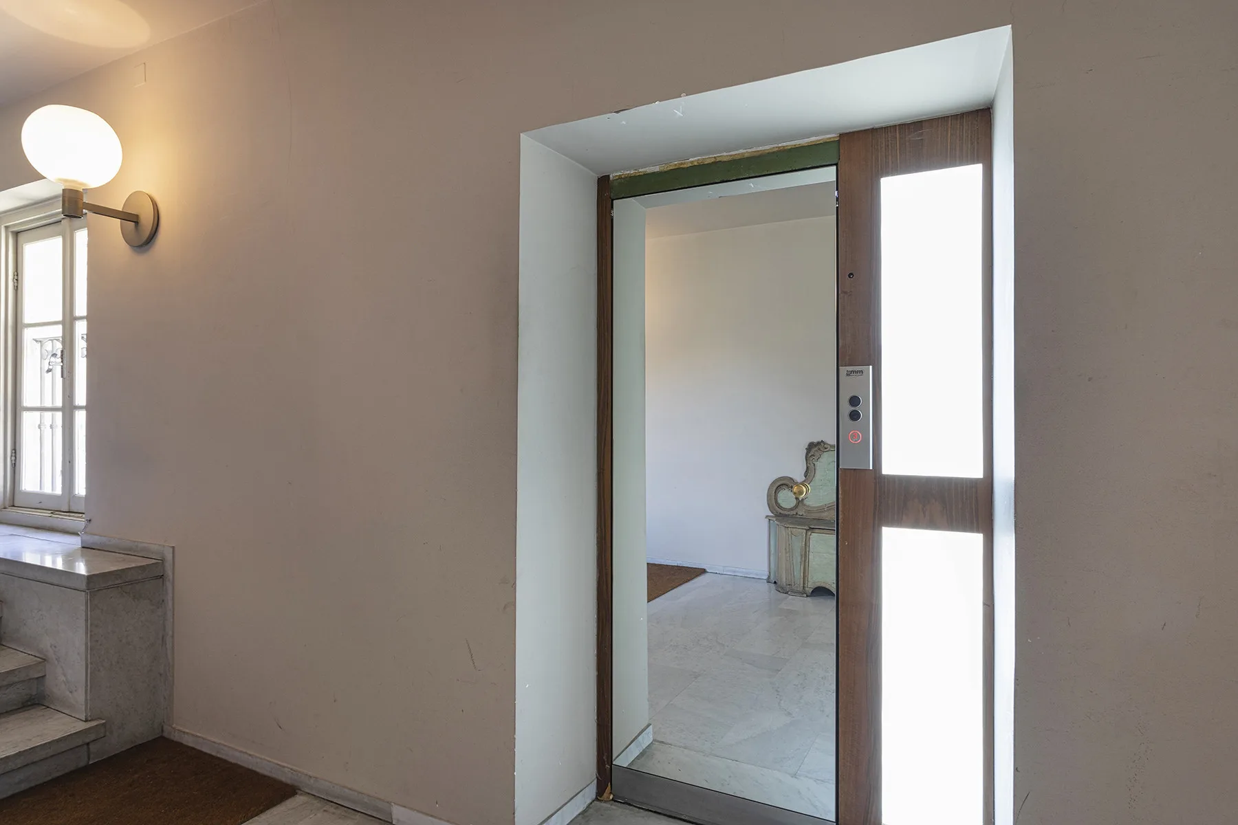 Un pasillo interior luminoso da a una habitación con suelo de baldosas.