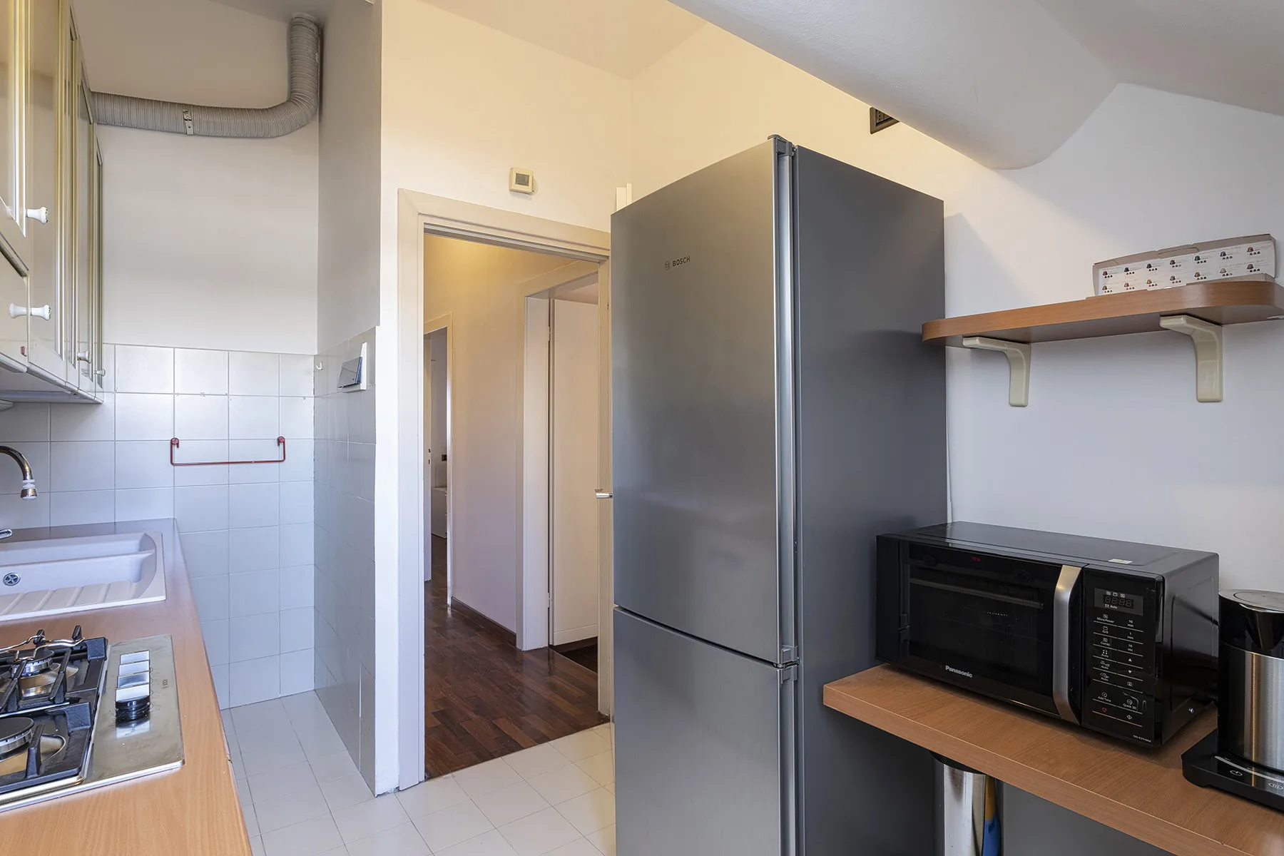 Una cocina compacta con refrigerador, microondas y zona de cocción.