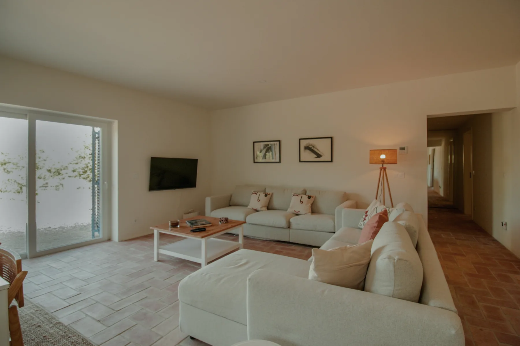 A bright living room with sectional seating, a coffee table, and sliding glass doors.
