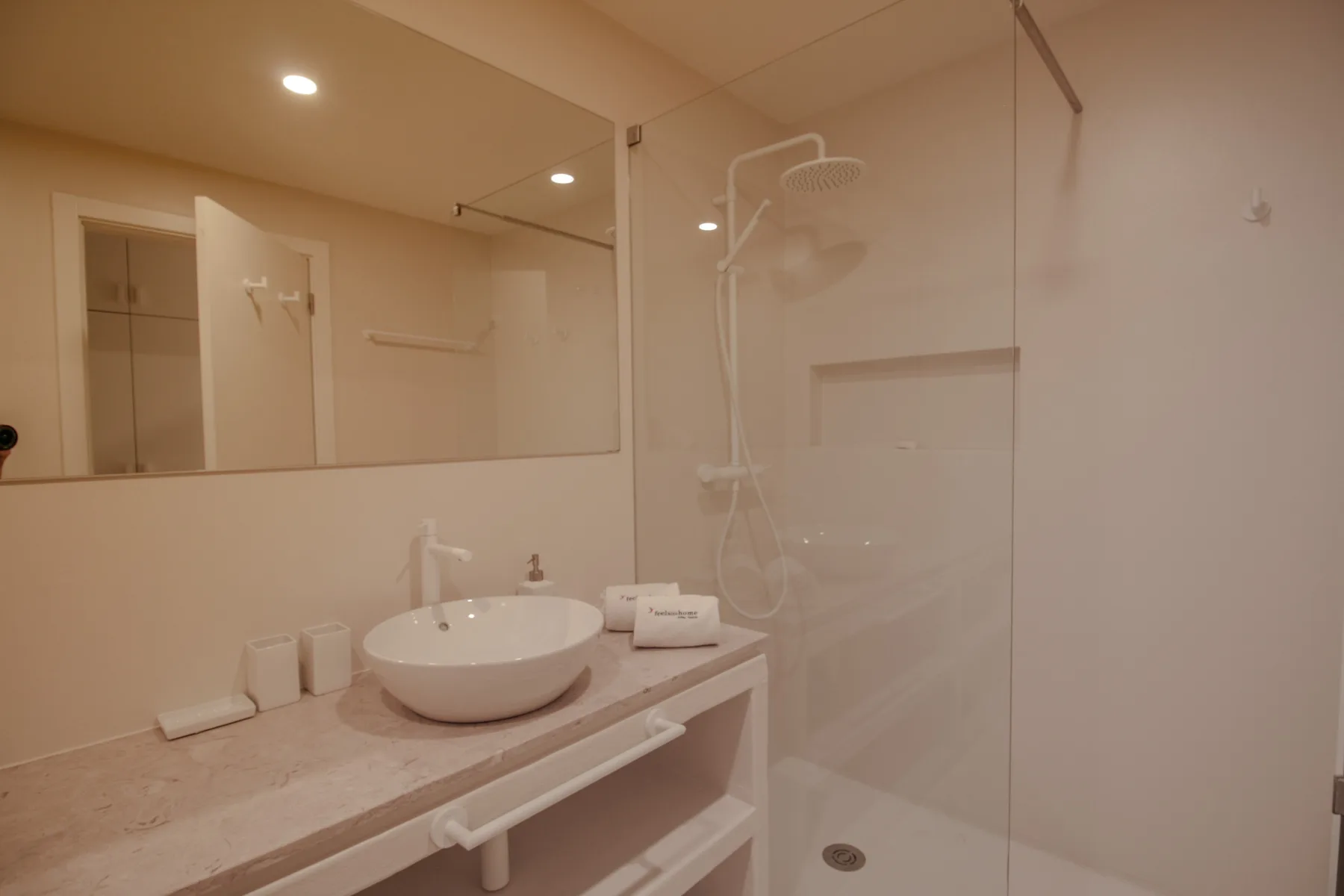 A bright bathroom with a countertop sink and glass shower.