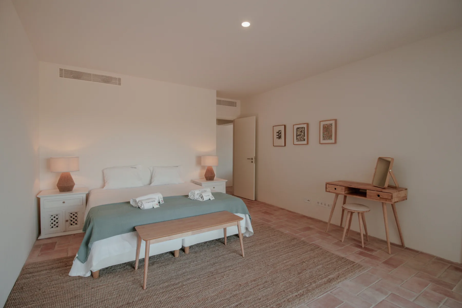 A bedroom with a bed, bedside tables, and a small writing desk.