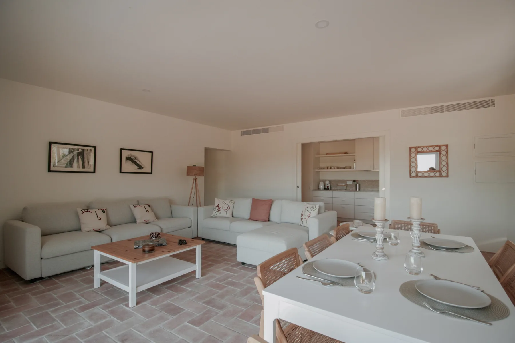 A bright living and dining area with light-colored seating and a set dining table.