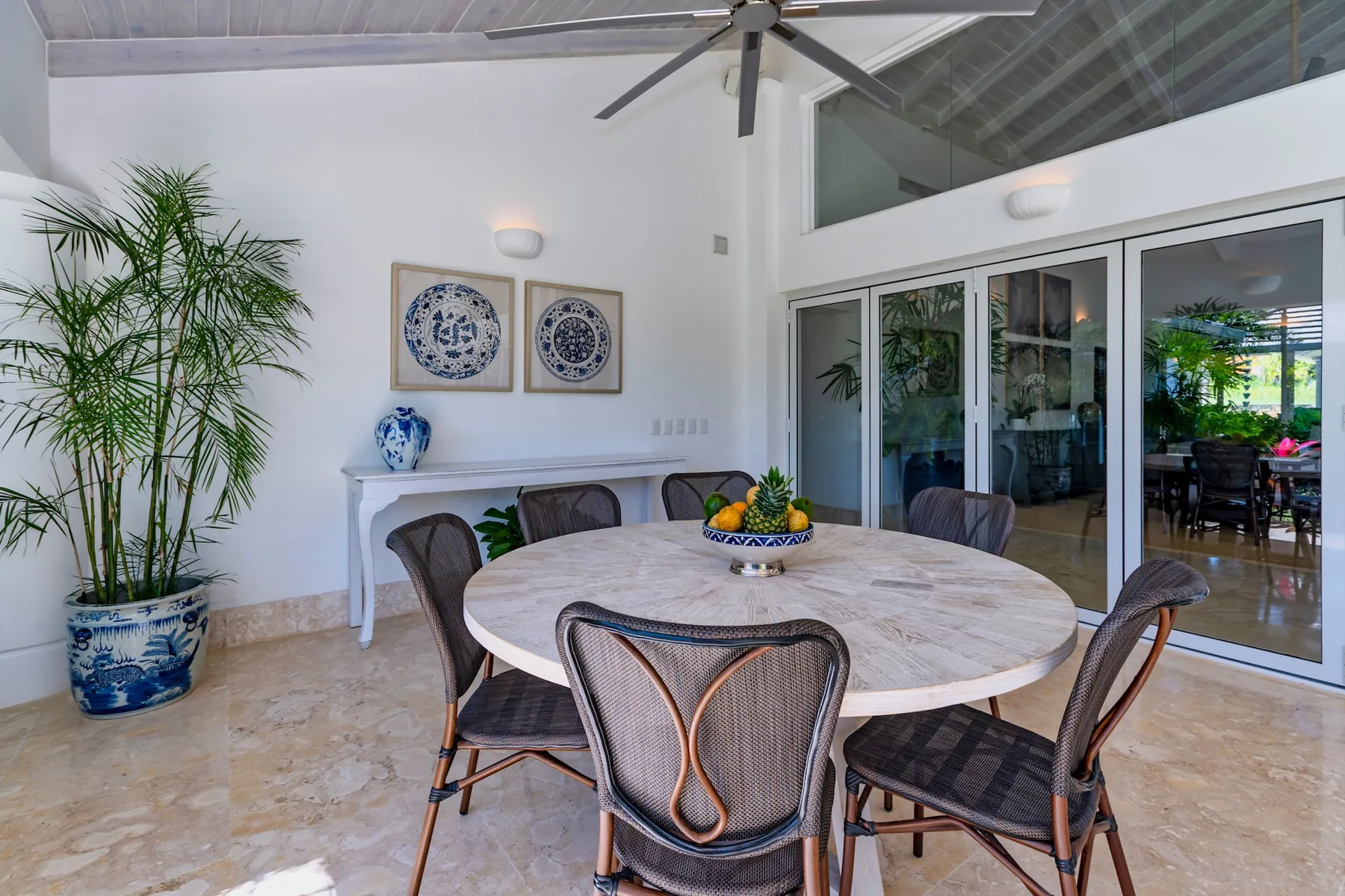 A dining area with a round table, chairs, and glass doors opening to a patio.