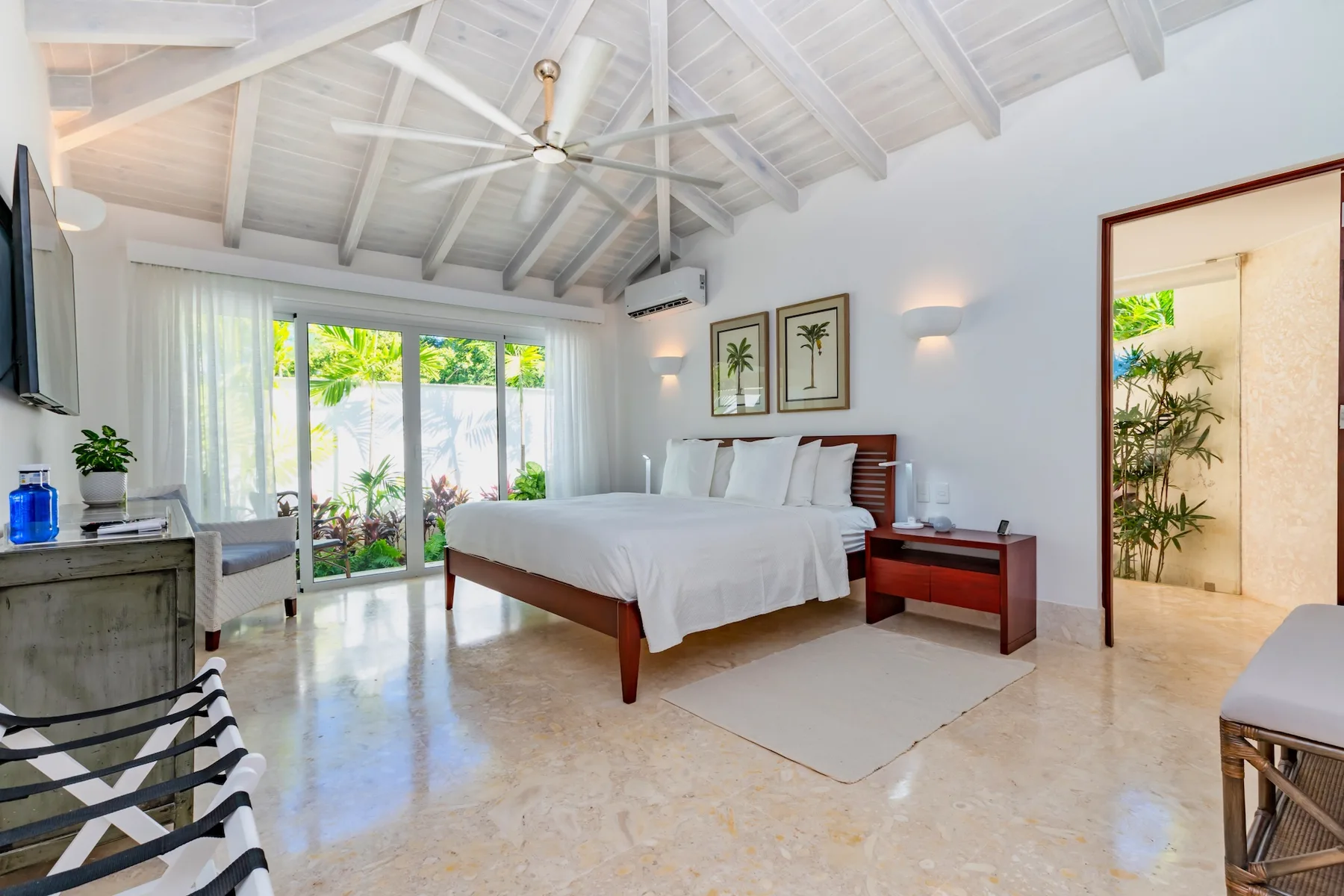 A bright bedroom with a large bed beneath a white vaulted ceiling.