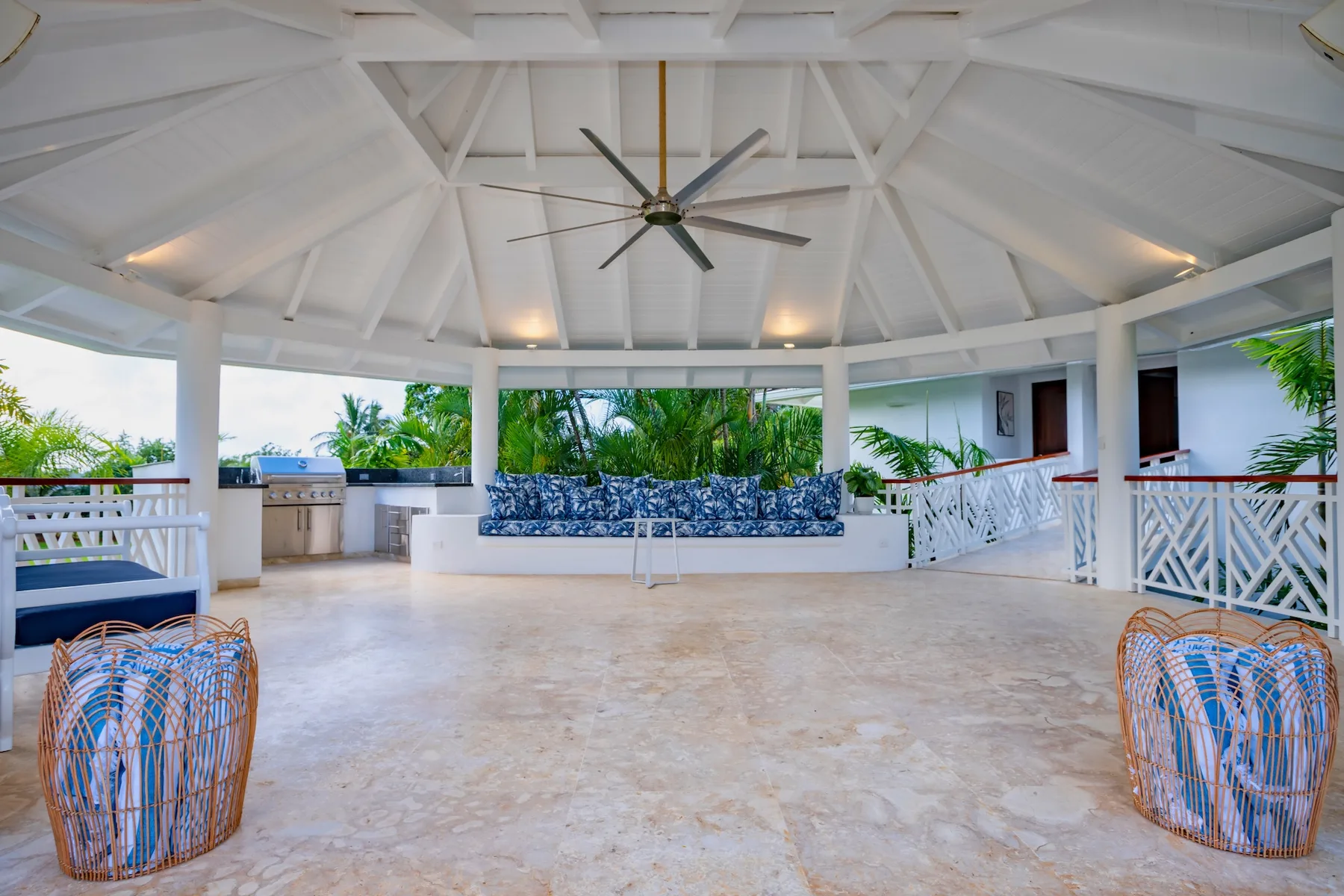 An open-air covered lounge with a large ceiling fan and built-in seating.