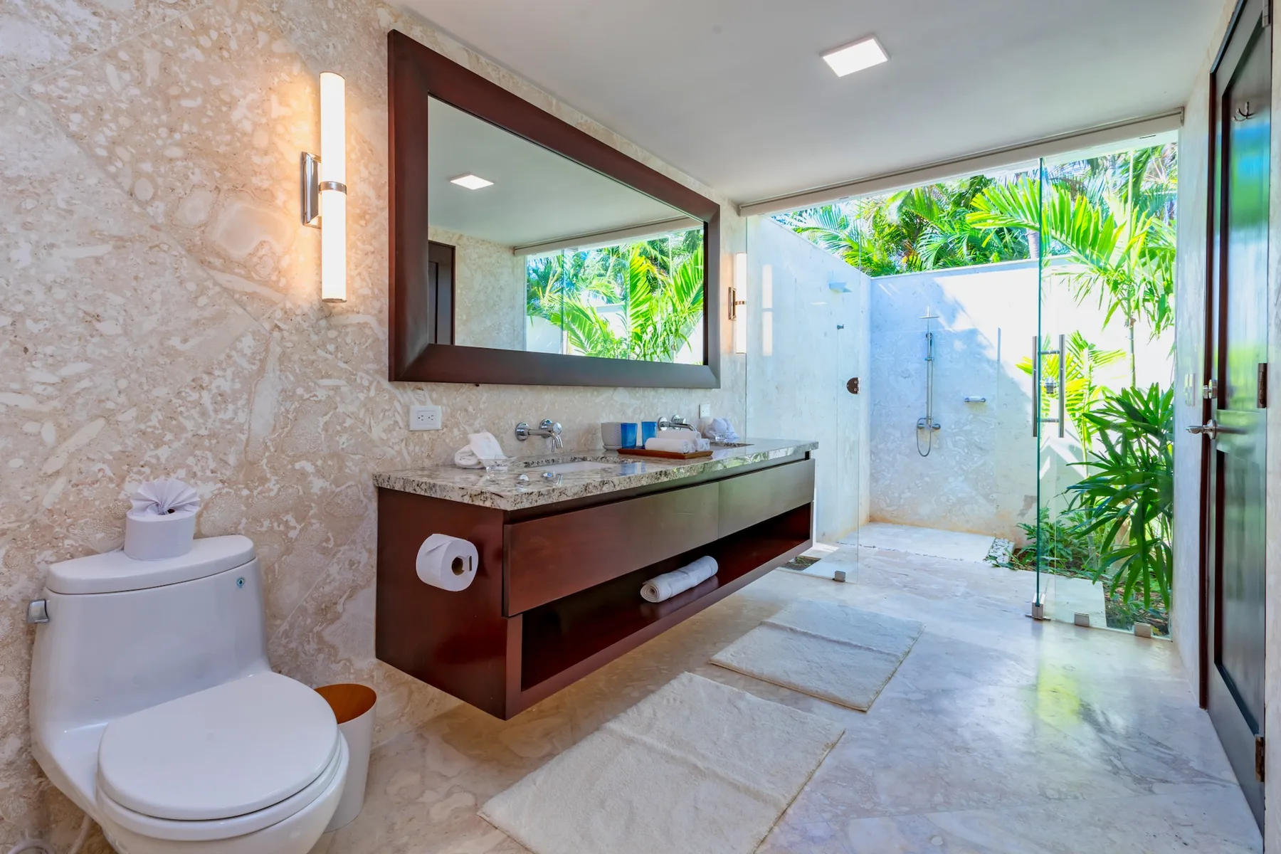 A bathroom with a vanity, toilet, and open shower area.