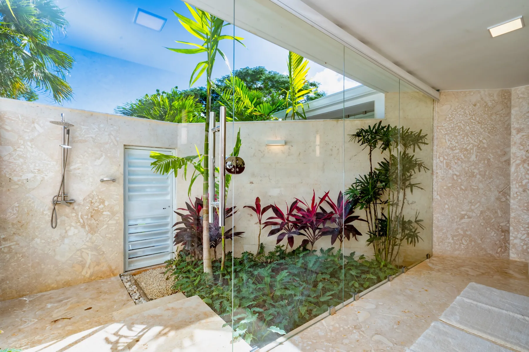 A bright bathroom with a glass shower and a planted garden area.
