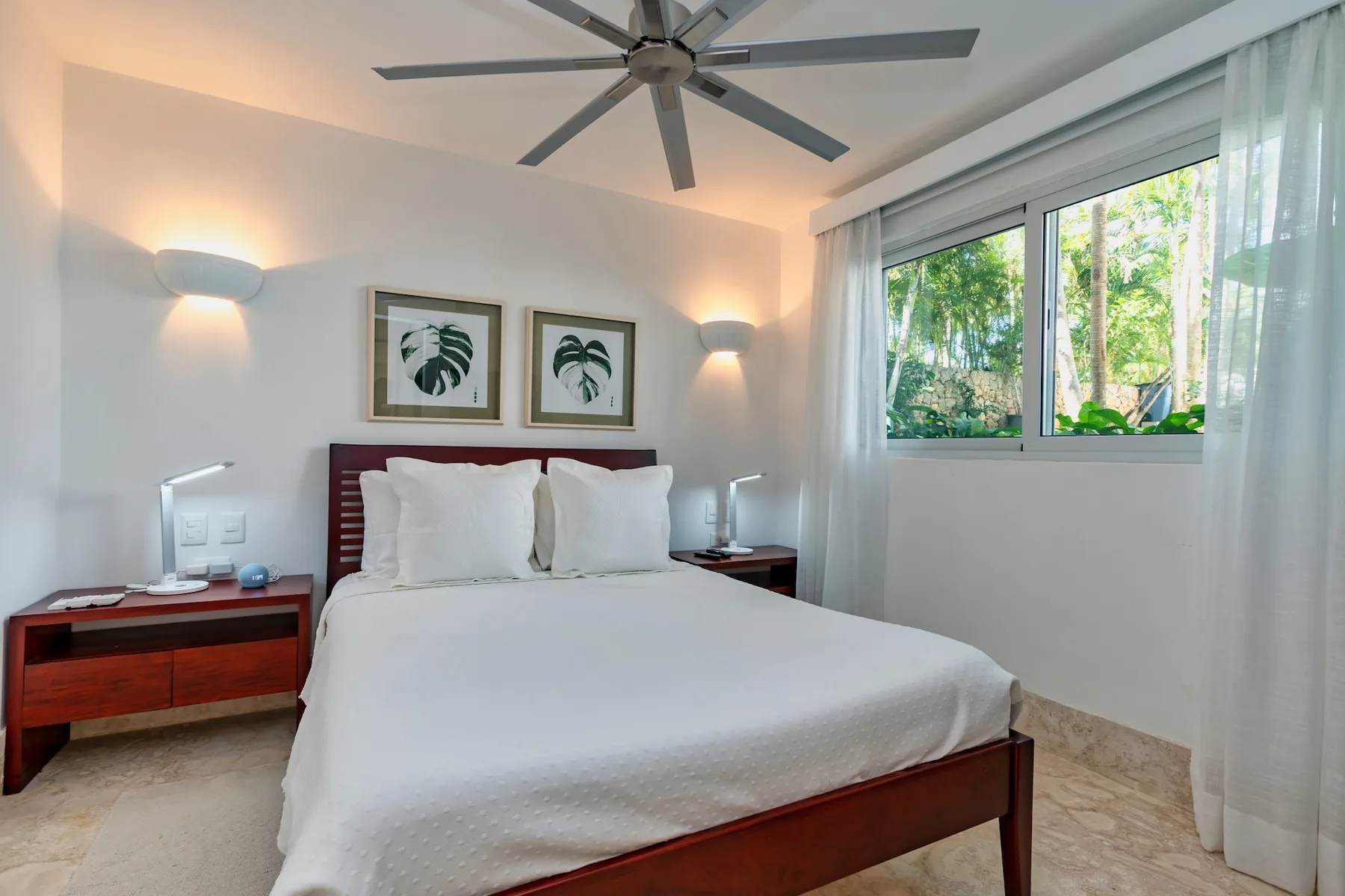 A bright bedroom with a neatly made bed and a large window.