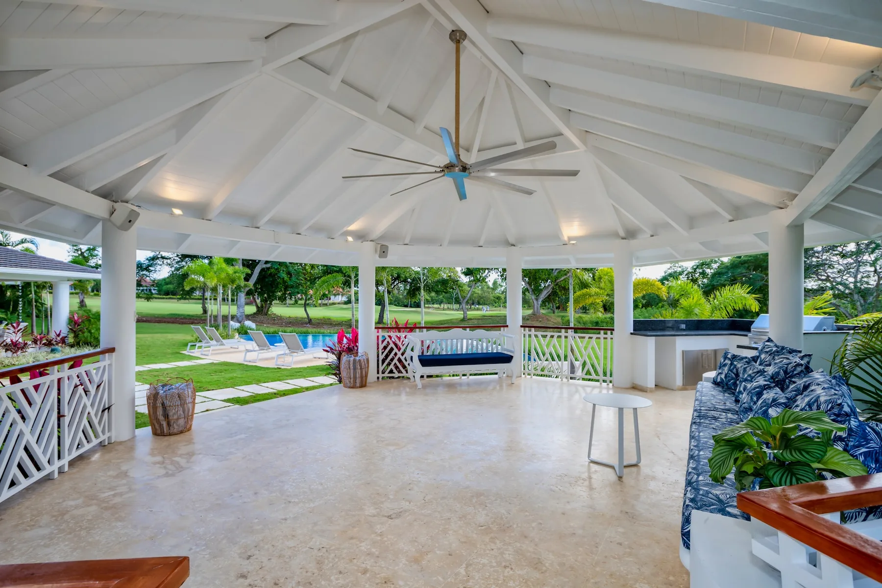 An open-air covered patio with seating and a view of the garden.