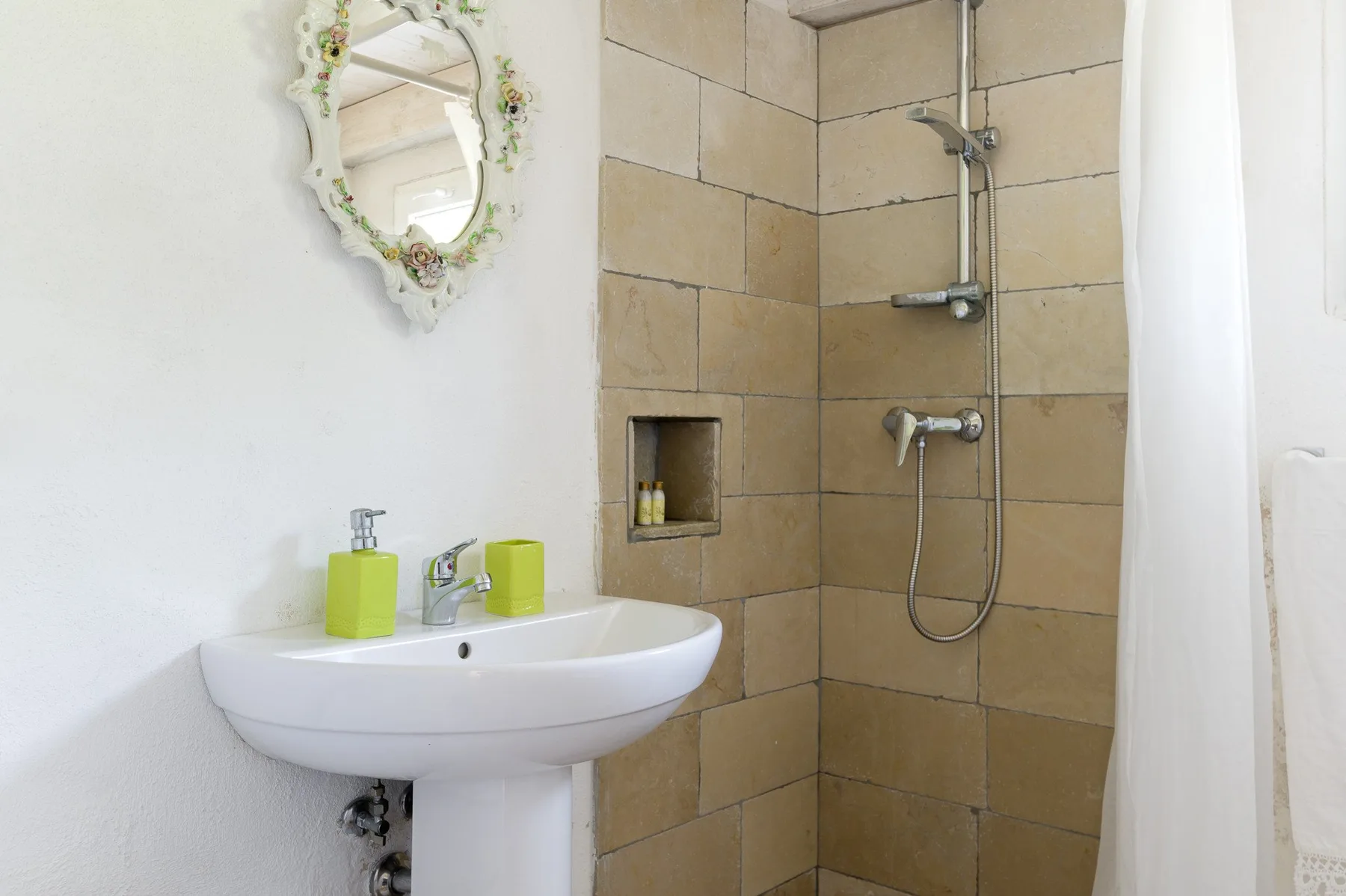 A bathroom with a pedestal sink and tiled shower.